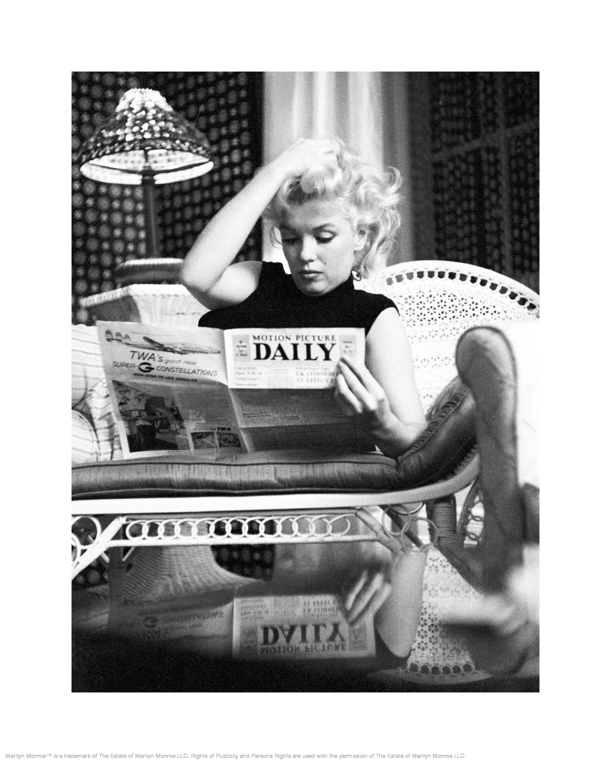 Póster de Marilyn Monroe en blanco y negro, leyendo el periódico Motion Picture Daily sentada en un sillón.