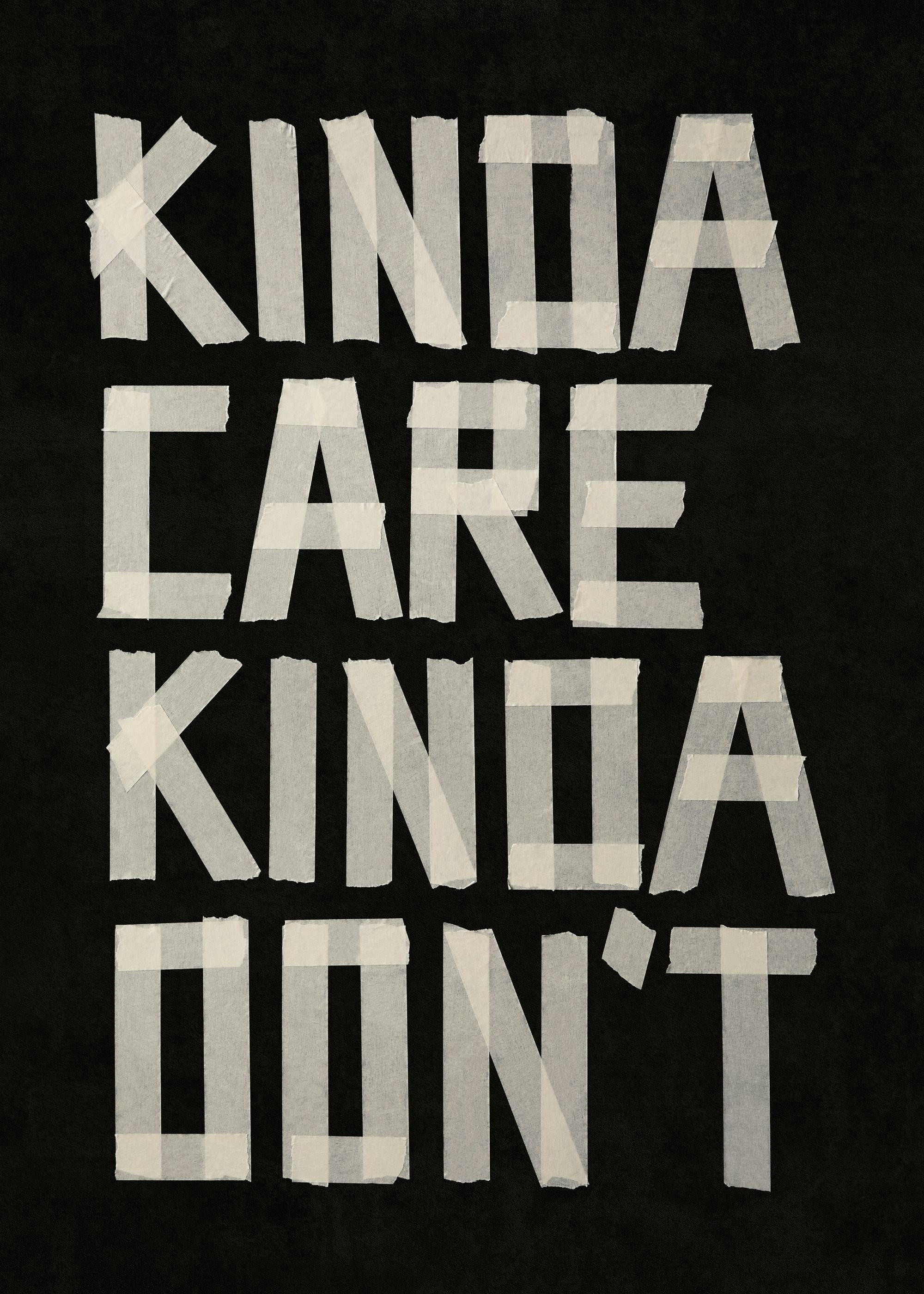 En plakat med teksten KINDA CARE KINDA DONT dannet av hvit maskeringstape på svart bakgrunn.