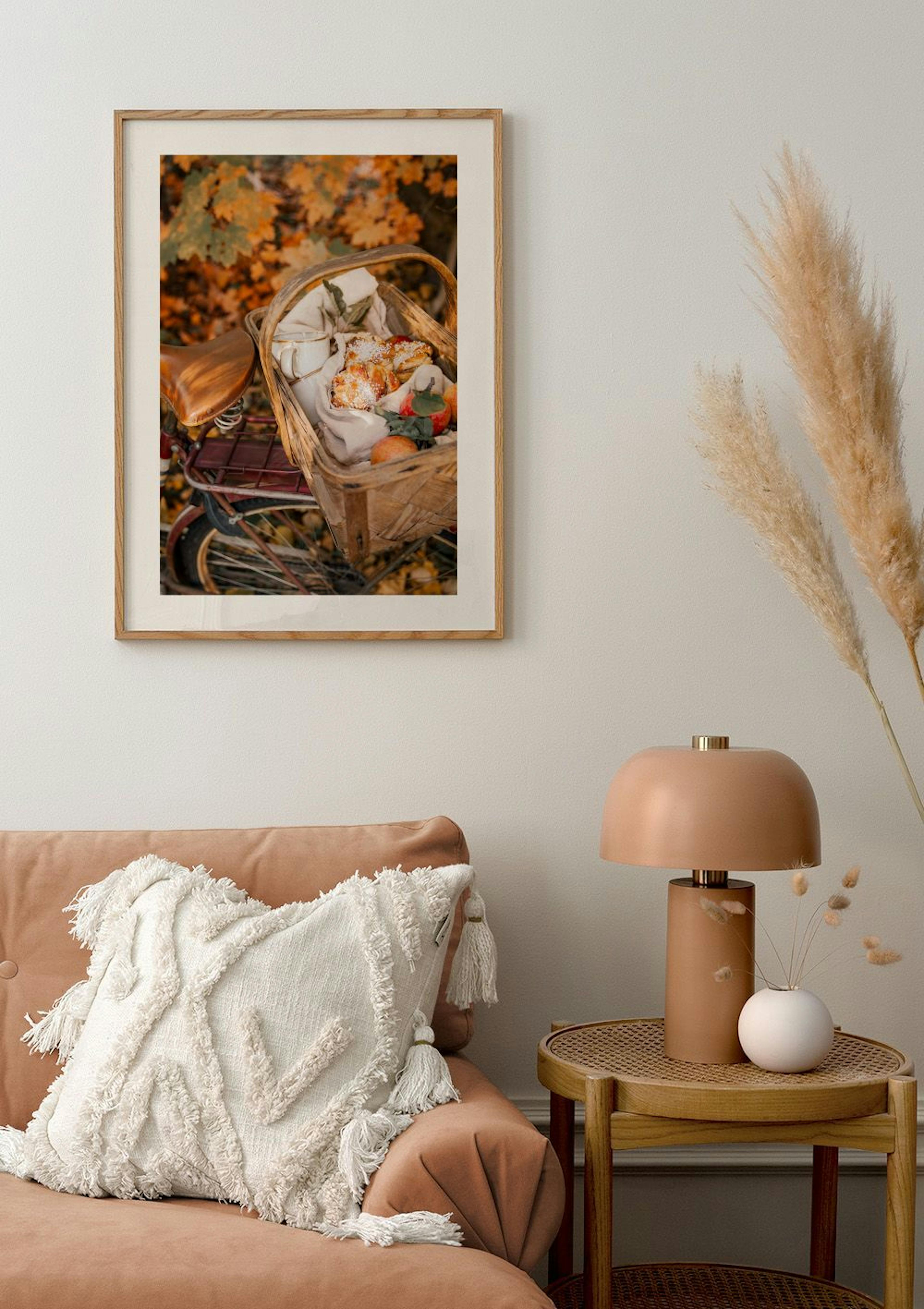 A poster featuring a picnic basket on a bicycle with autumn leaves in the background, displayed above a peach sofa.