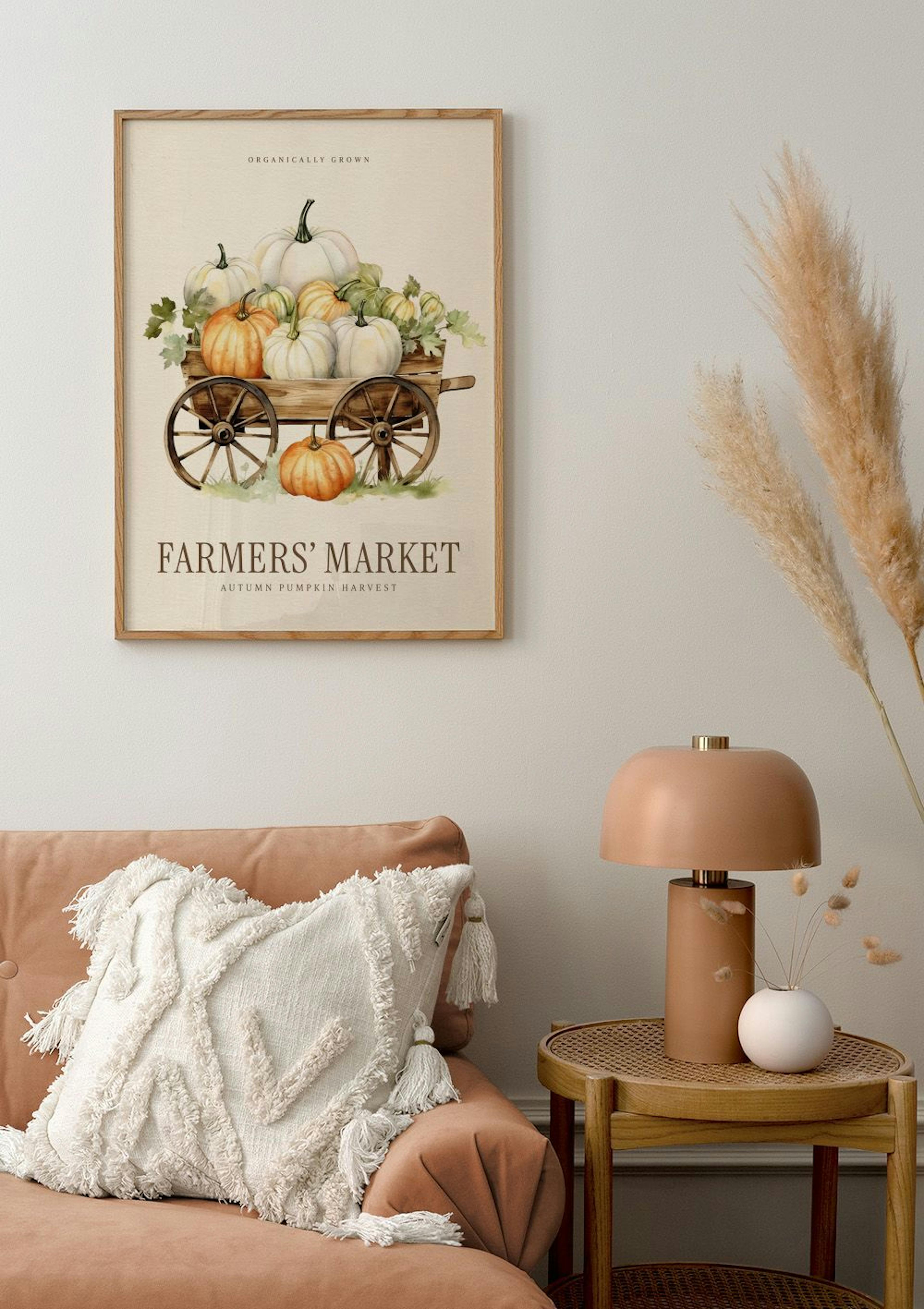 A poster of a wooden cart overflowing with white and orange pumpkins, hanging above a peach sofa in a cosy living room.
