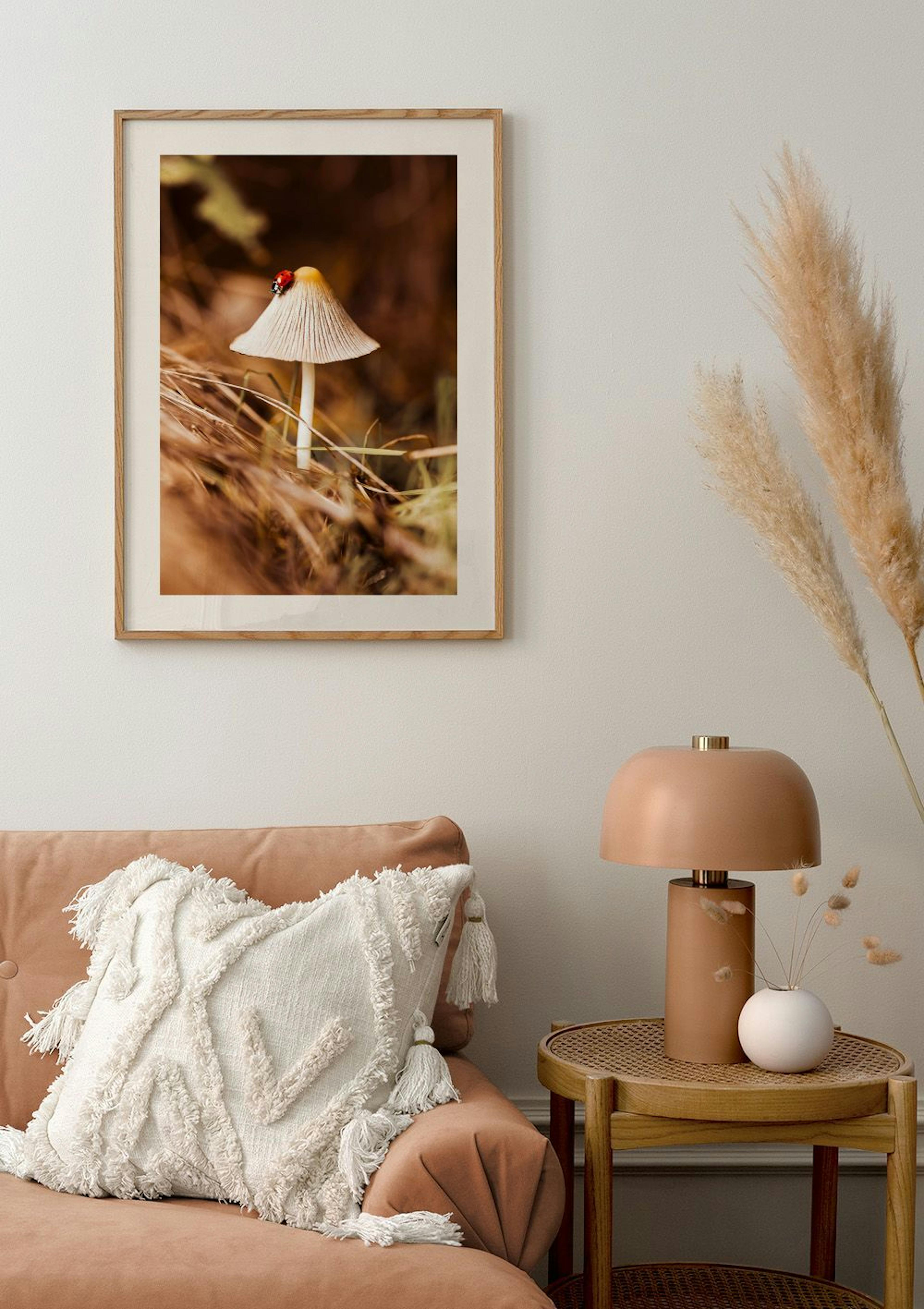 A poster of a white mushroom with a red ladybug on its cap, displayed above a peach sofa in a living room.
