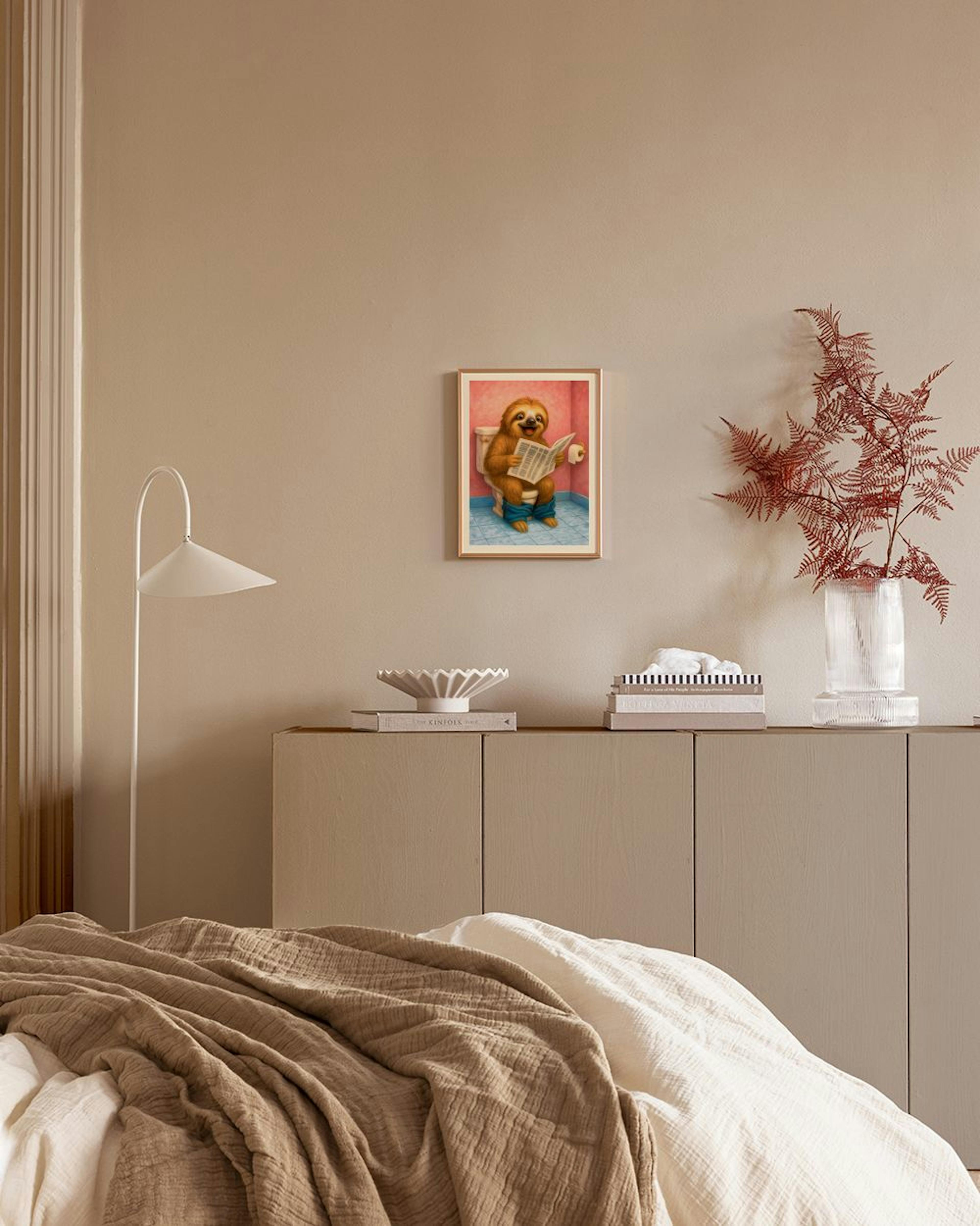A humorous poster of a sloth on a toilet reading a newspaper, hanging above a bedside cabinet in a bedroom.