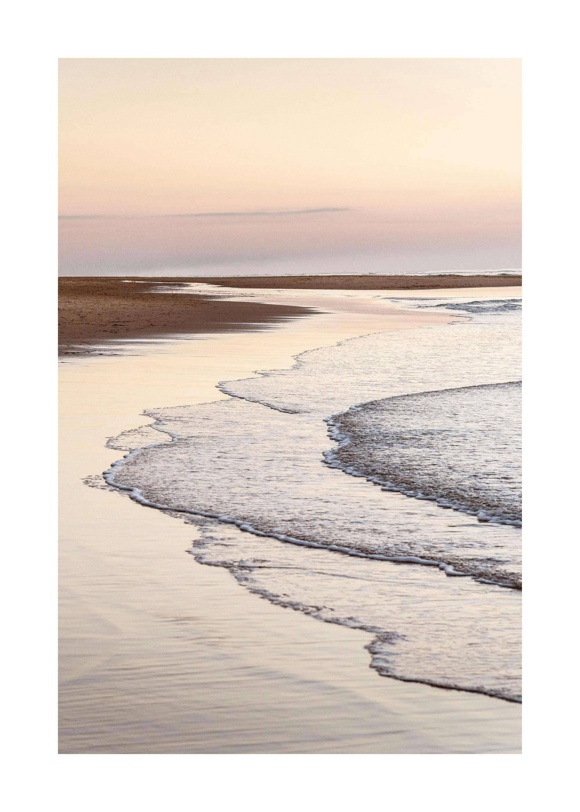 Poster dune plage sereine au coucher du soleil, avec la mer et le sable aux teintes dorées et rosées.