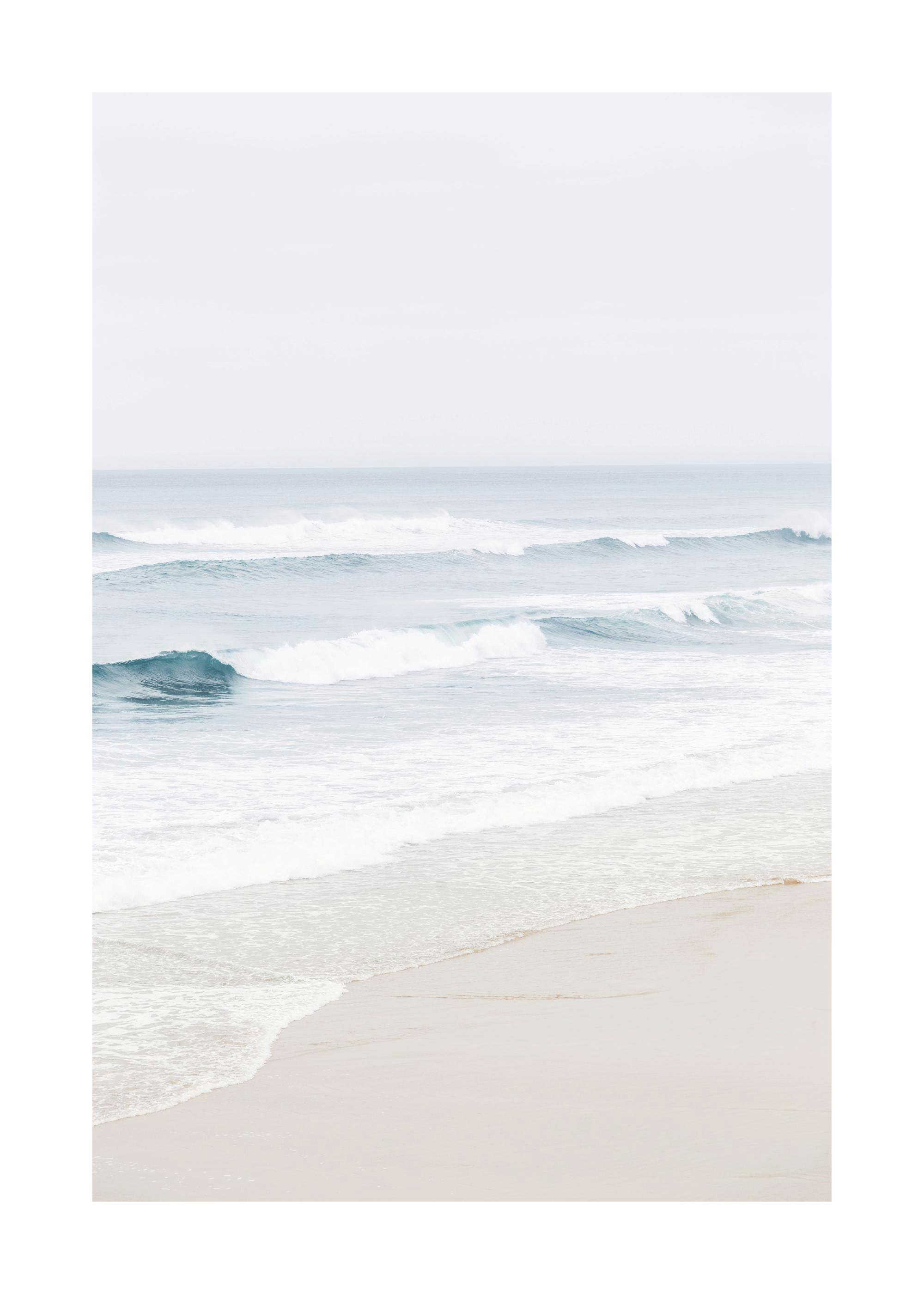 Poster de vagues bleues claires déferlant sur une plage de sable beige sous un ciel pâle.