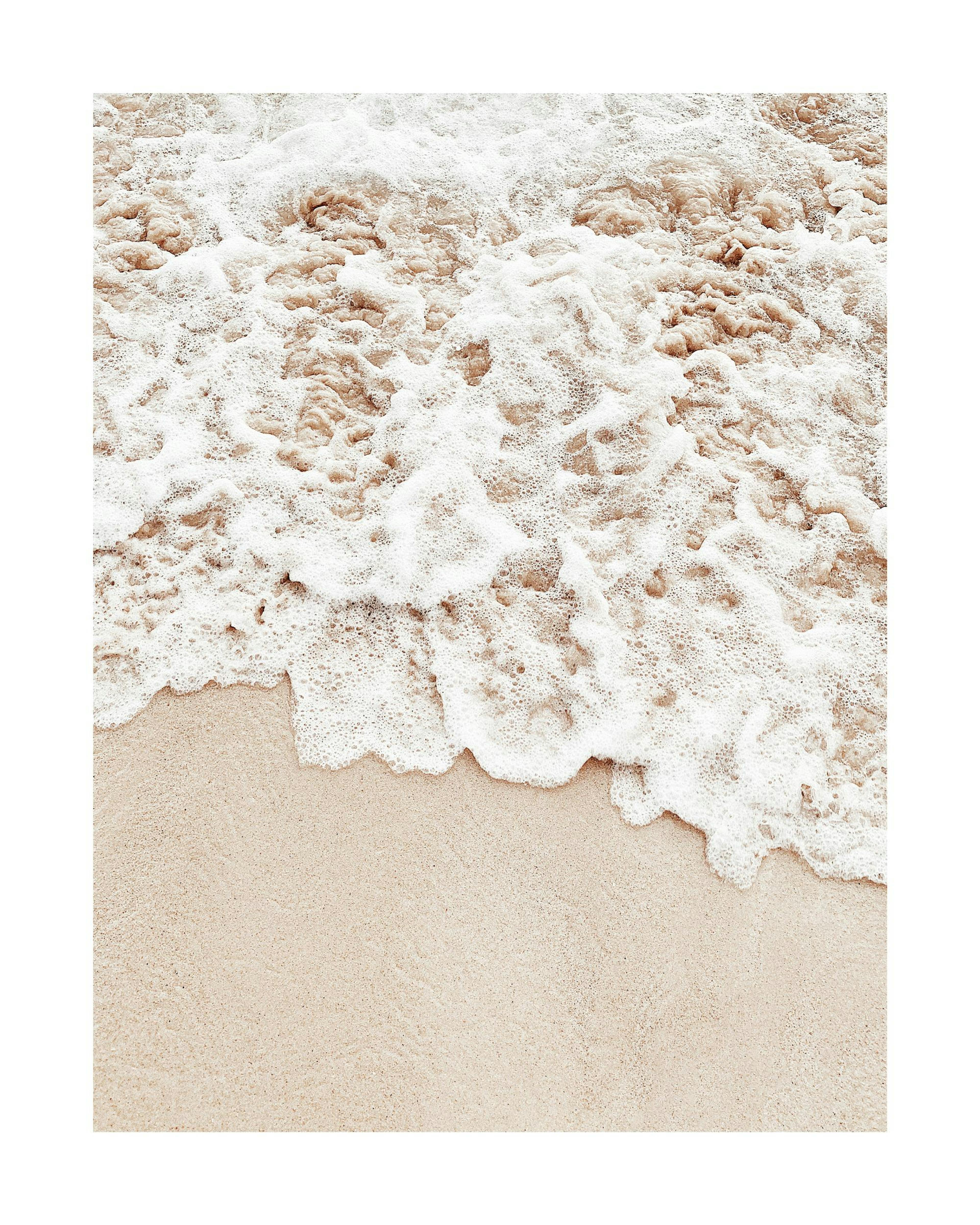 A poster depicting a close-up of foamy white ocean waves washing onto light brown sand.