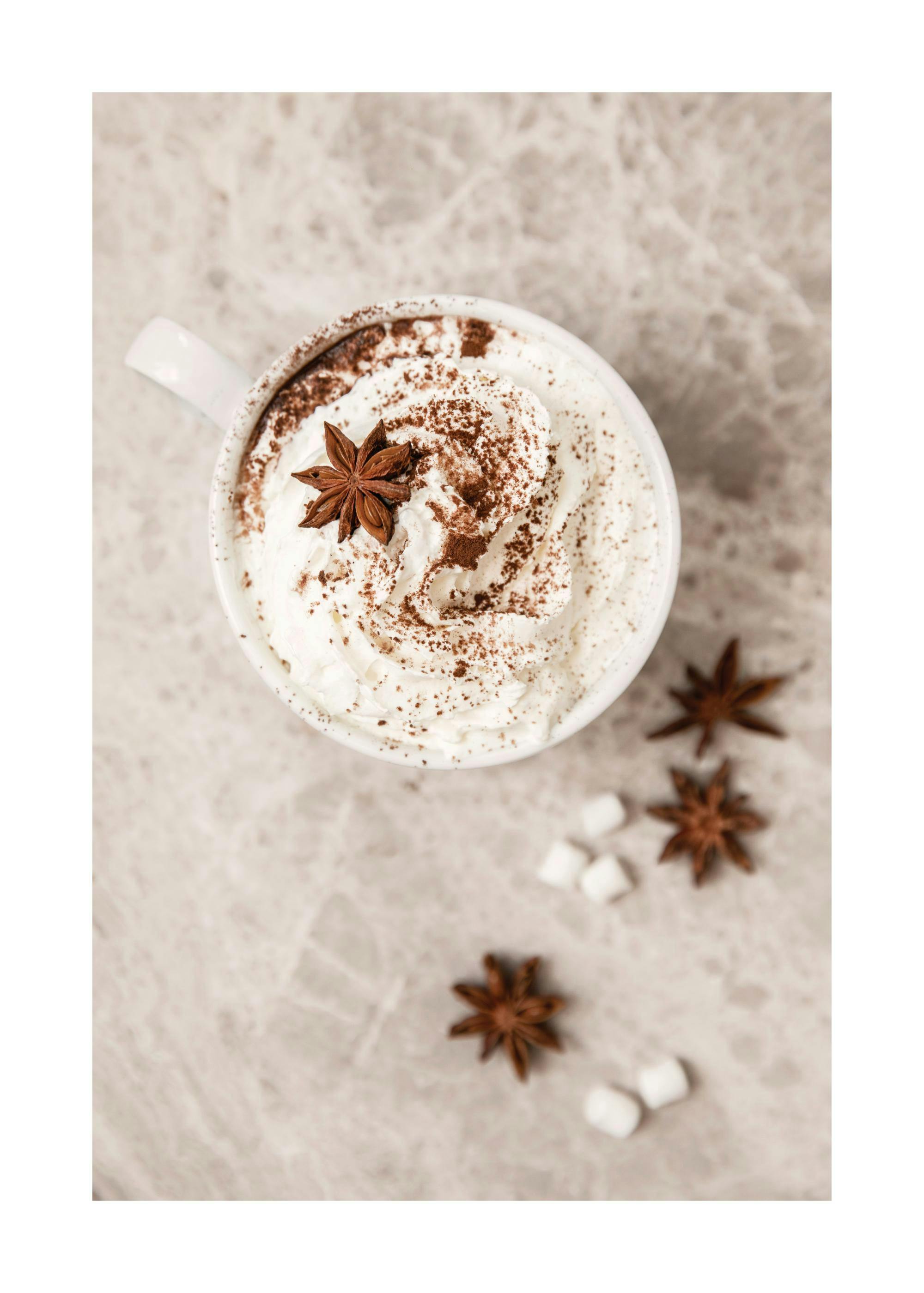 Een poster van een kop warme chocolademelk met slagroom, bestrooid met cacao en steranijs.