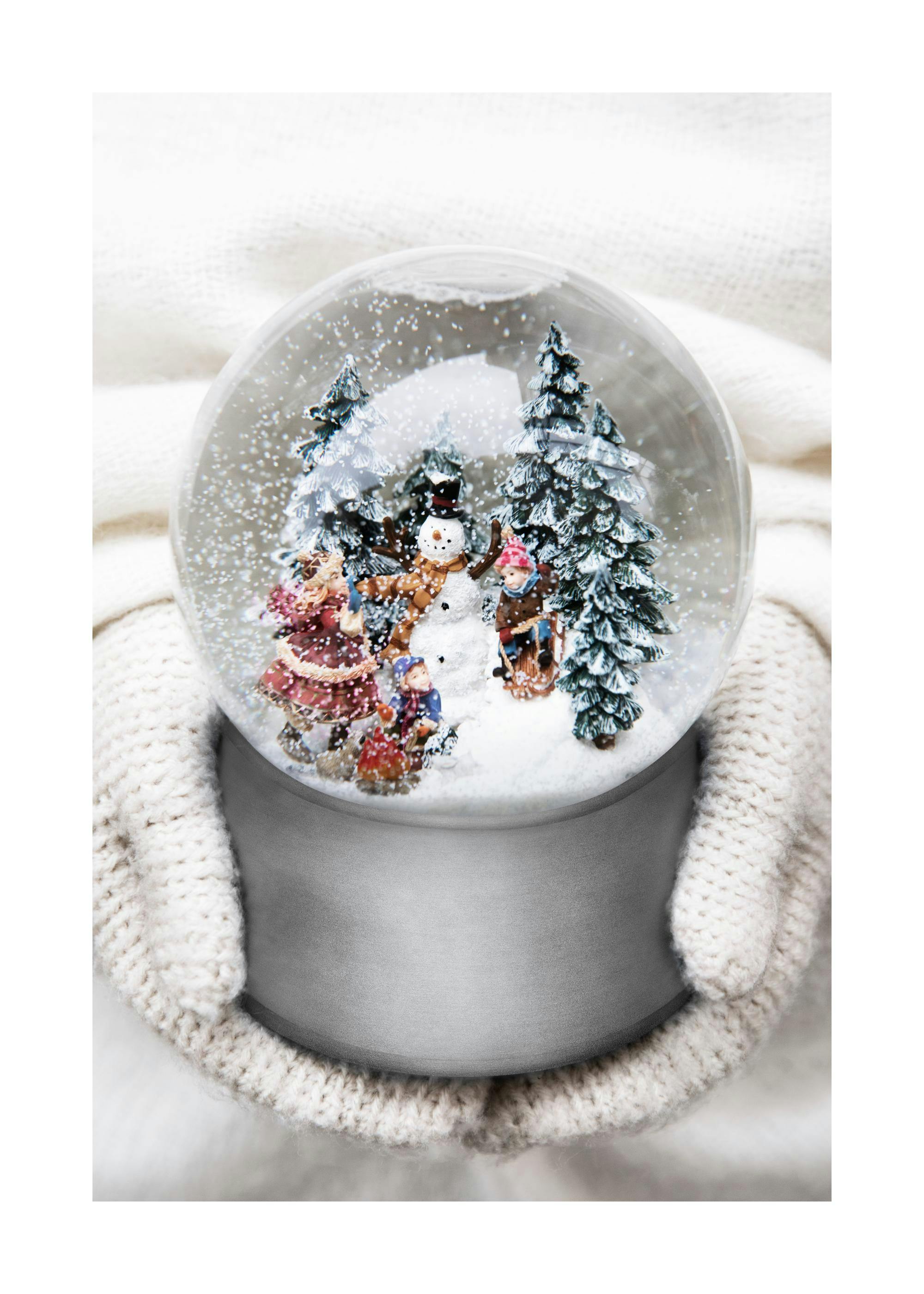A winter wonderland poster showing hands in white knitted mittens holding a snow globe with children and a snowman.
