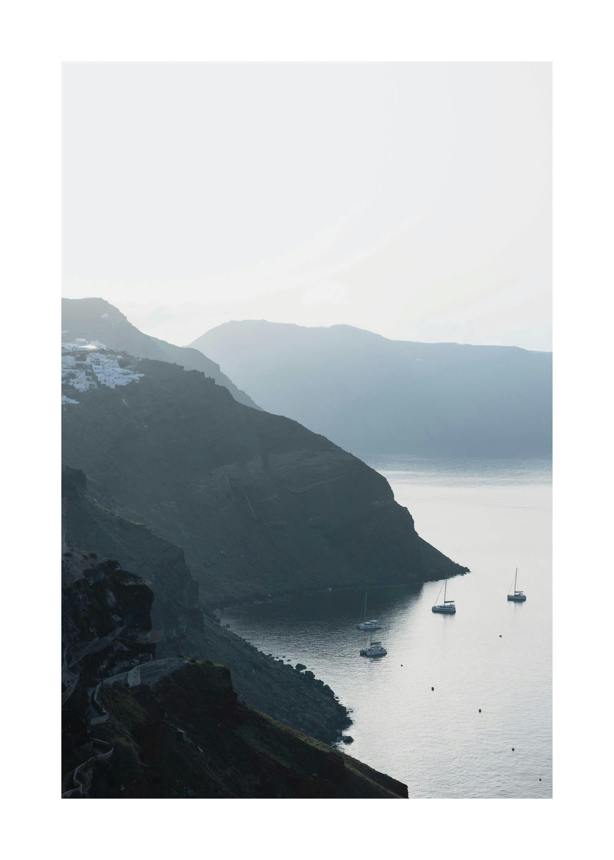 Tengerparti hegyoldalra épült fehér házak és hajók a vízen, szürke tónusú tájkép poster.