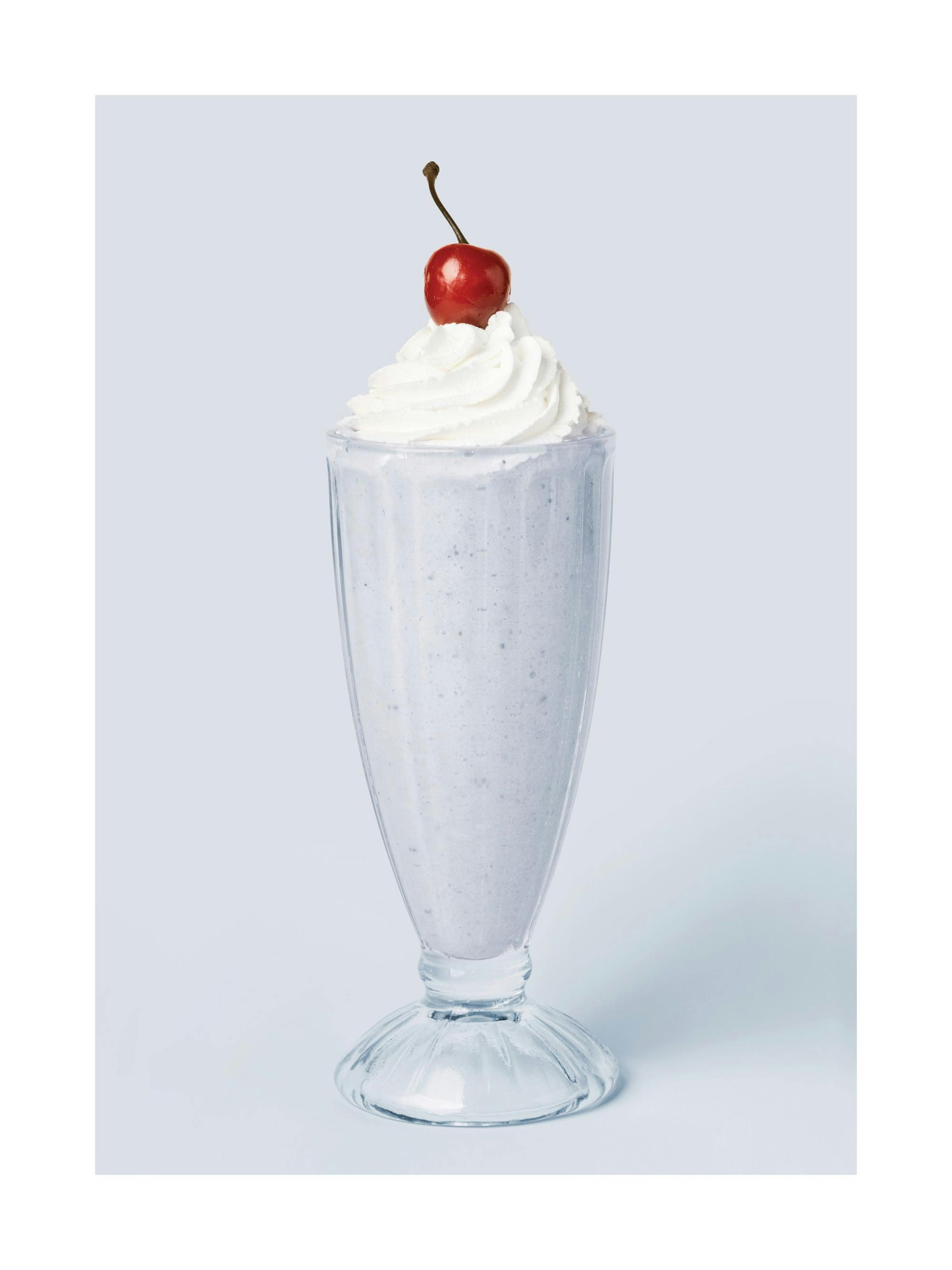 Een poster van een milkshake met slagroom en een kers op een lichtgrijze achtergrond.