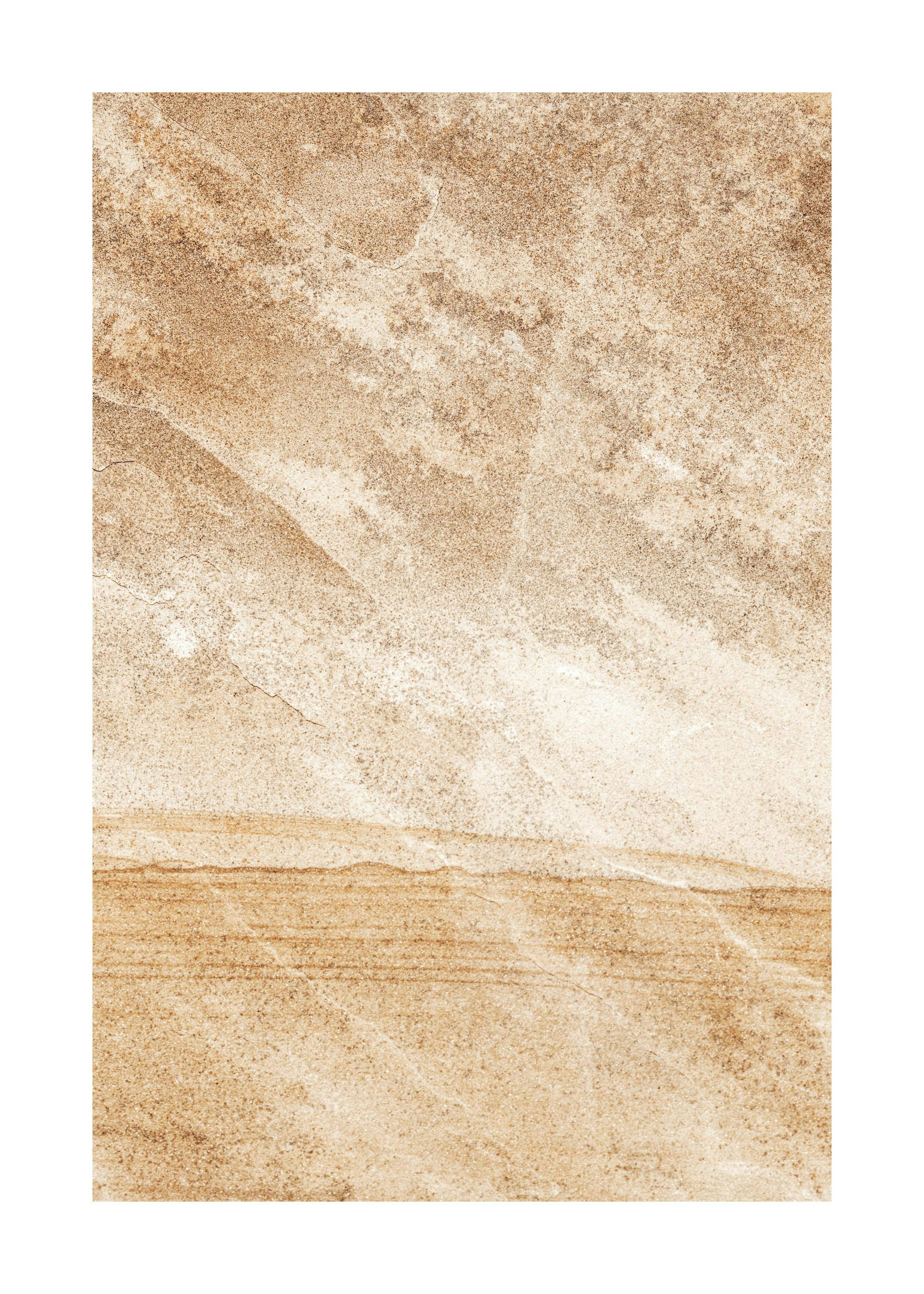 A poster with a brown and beige abstract design, resembling sand dunes or rock formations, hanging above a wooden chair with a b