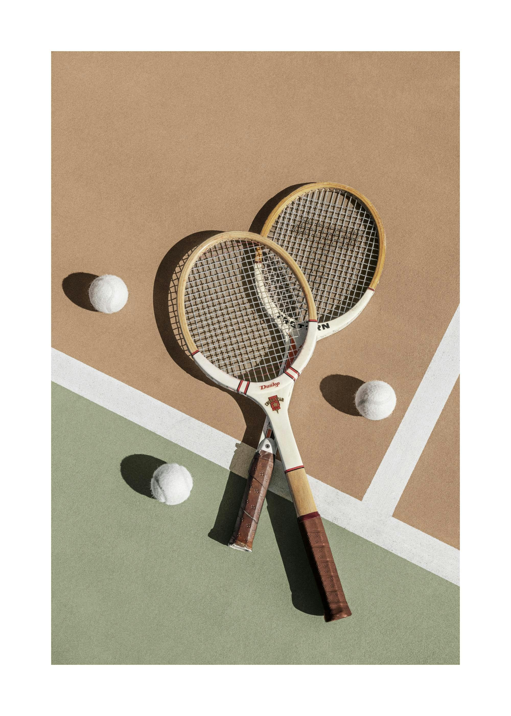 A poster featuring two vintage wooden tennis rackets and three white tennis balls on a green and tan court.