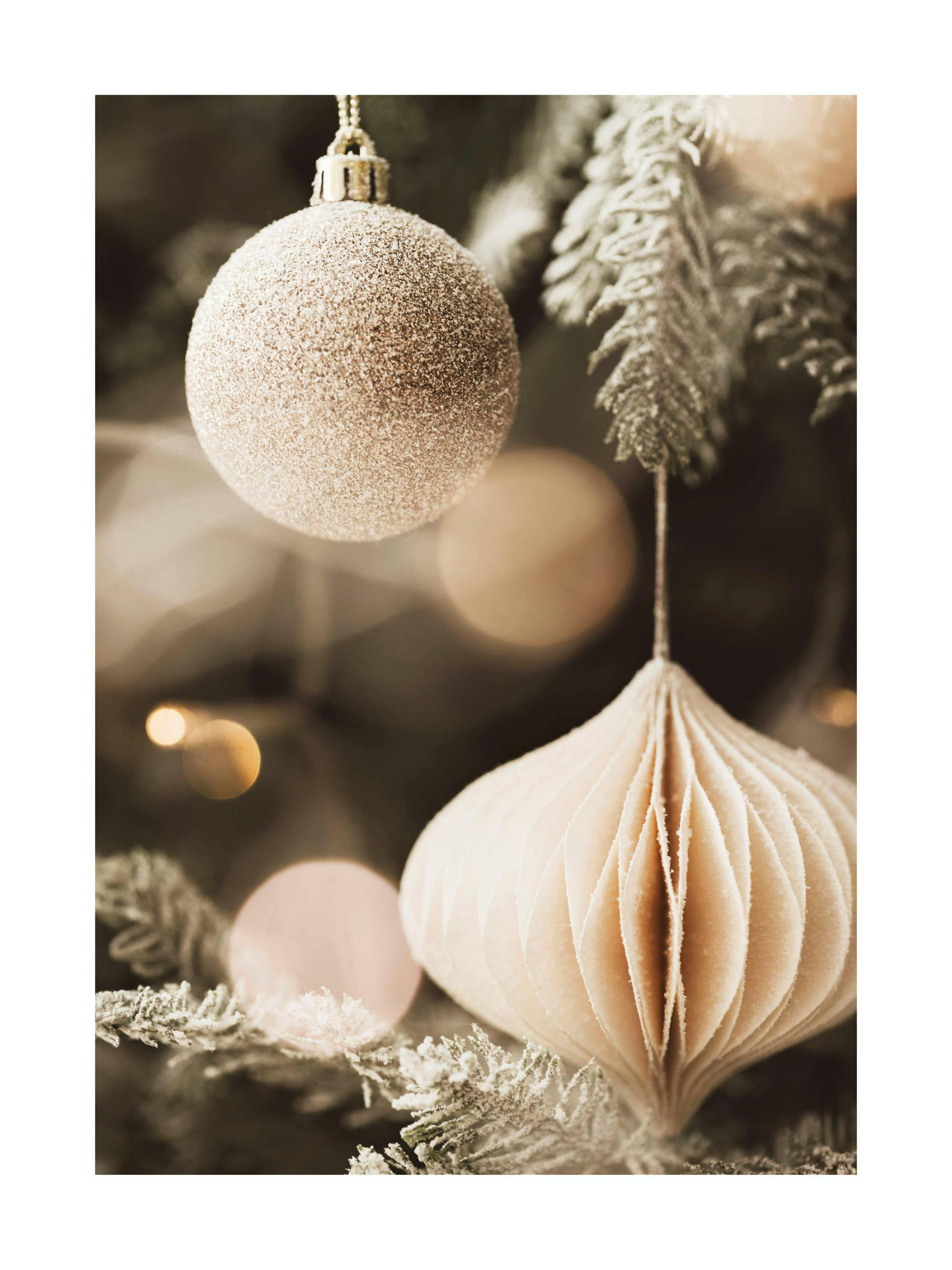 Juliste kuvaa joulukuusta, jossa on roikkuvat hohtavat ja valkoiset joulupallot sekä kuuraiset oksat.