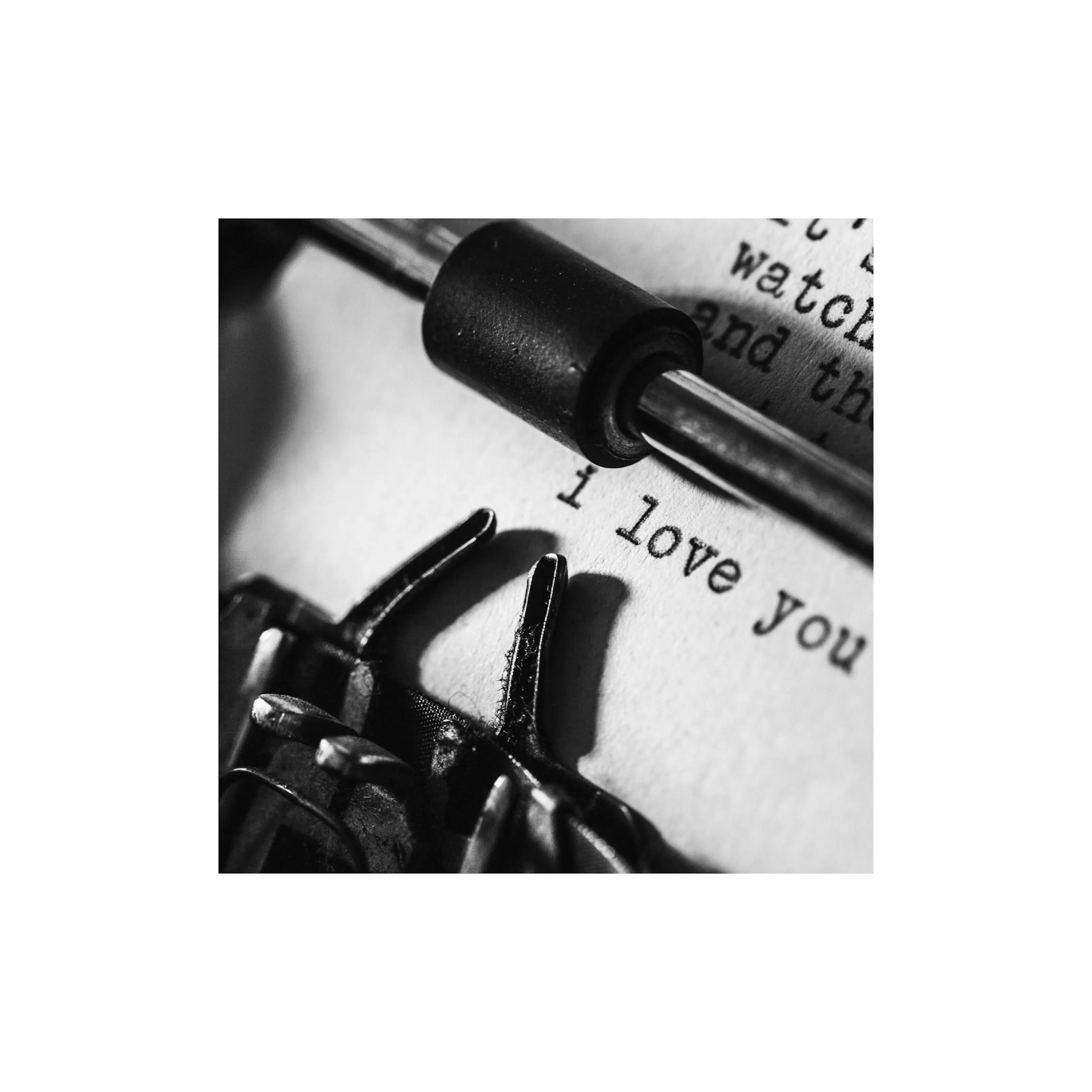 A black and white poster of a vintage typewriter with I love you typed on the paper.