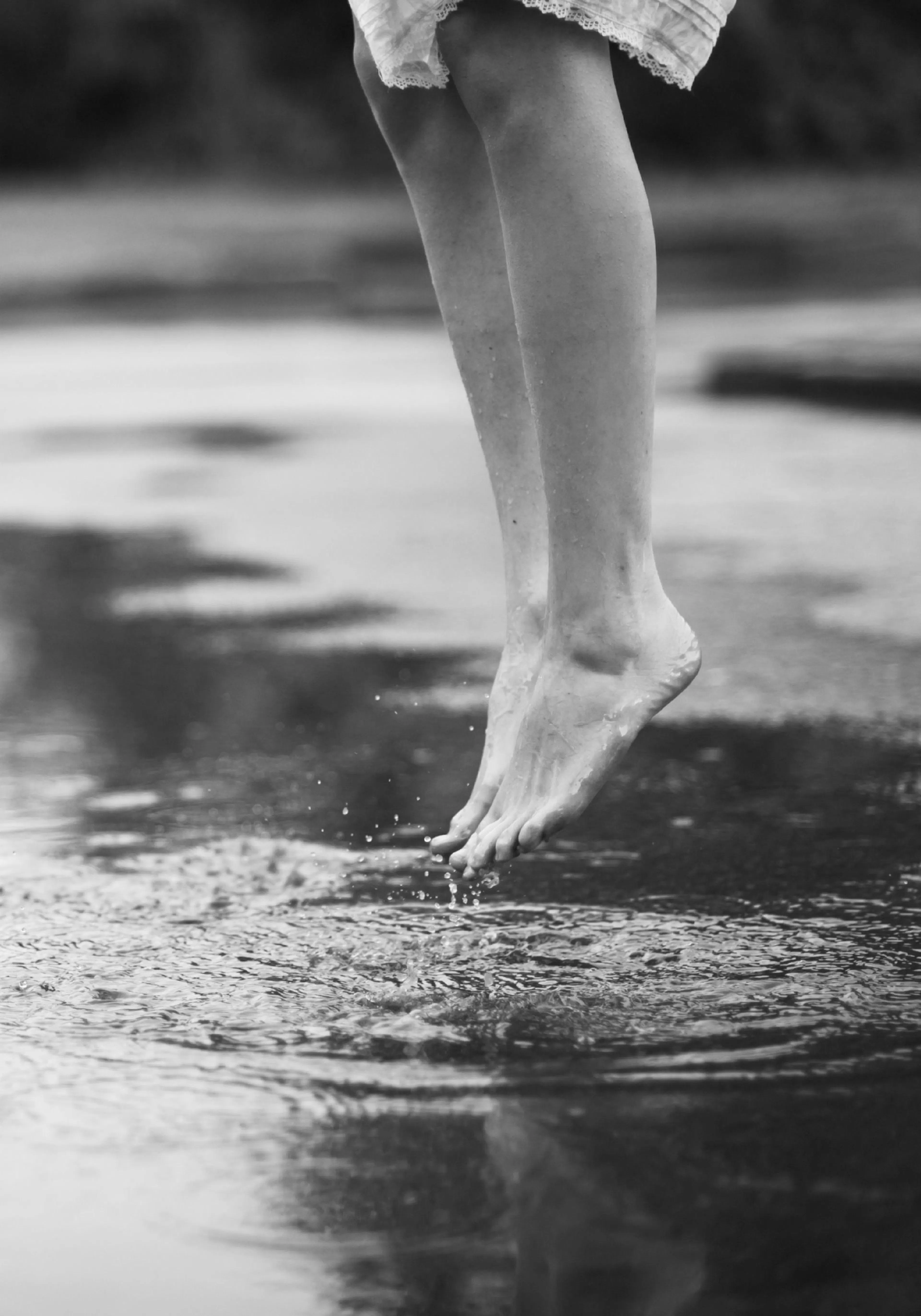 A poster depicting a persons bare legs and feet, hovering just above a water surface, creating splashes.
