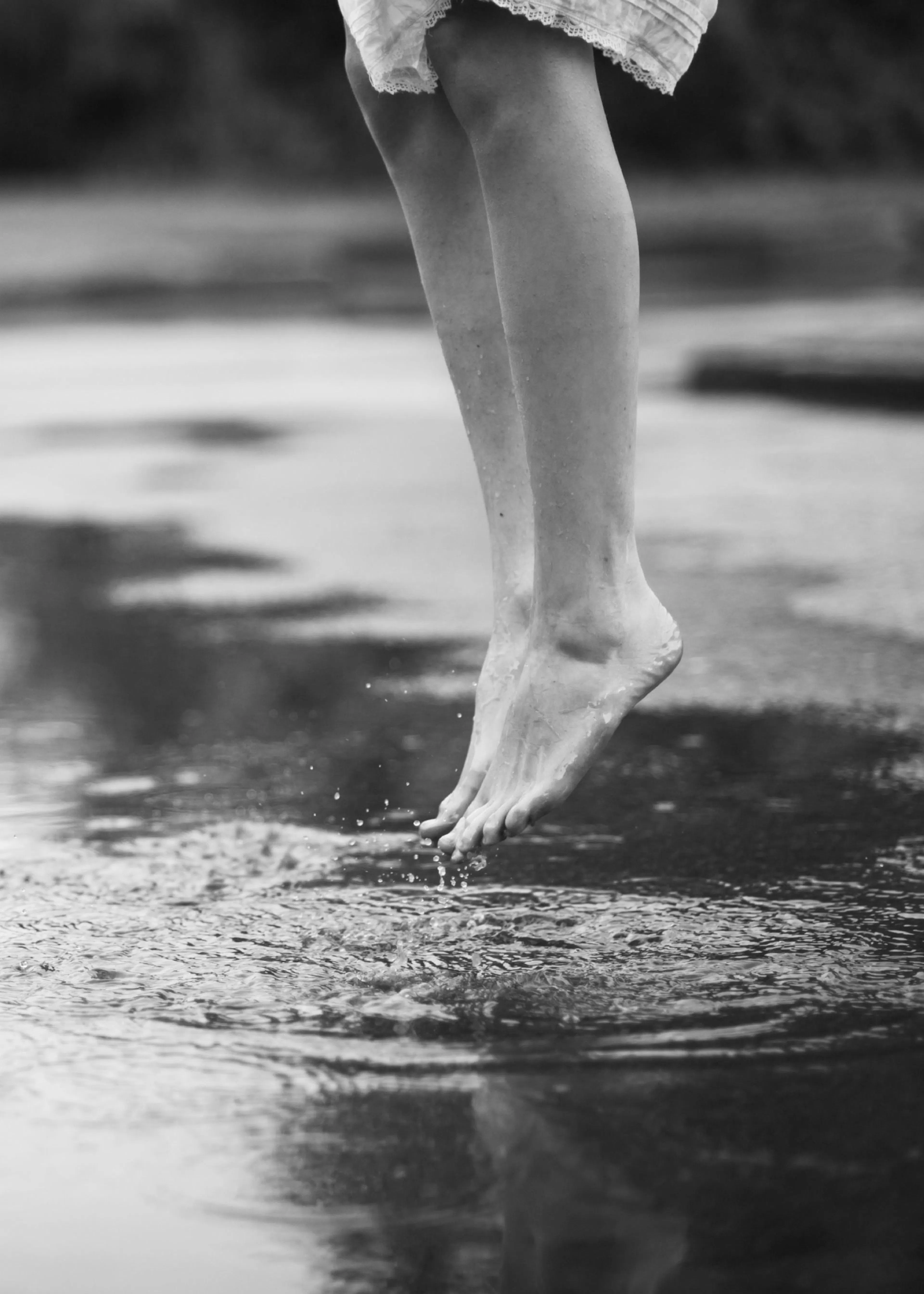 Mustavalkoinen juliste, jossa näkyy ihmisen jalat hypähdyshetkellä veden yllä, roiskeita syntyy.