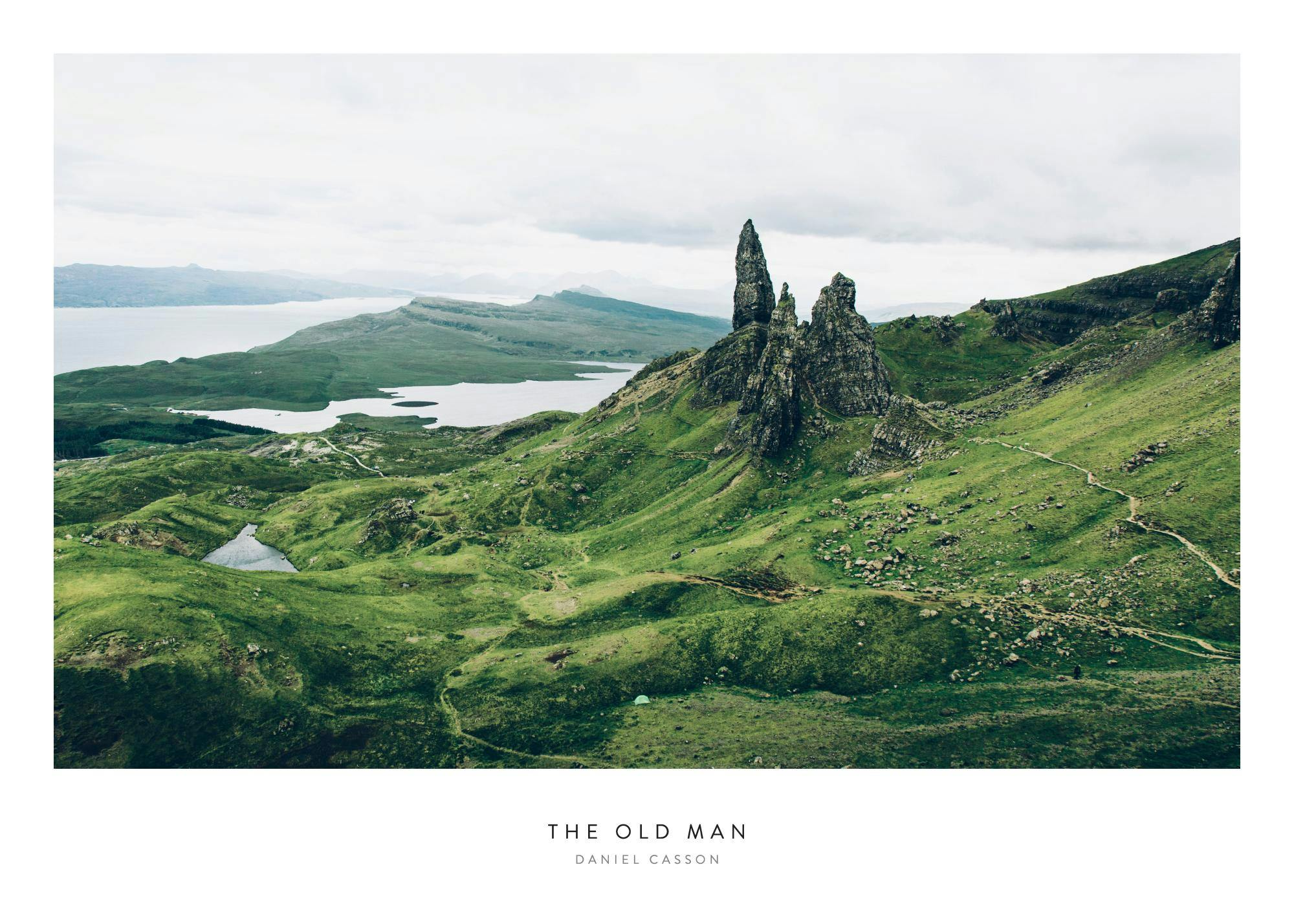 Poster dun paysage écossais avec le Old Man of Storr, une formation rocheuse sur une colline verdoyante surplombant un lac.