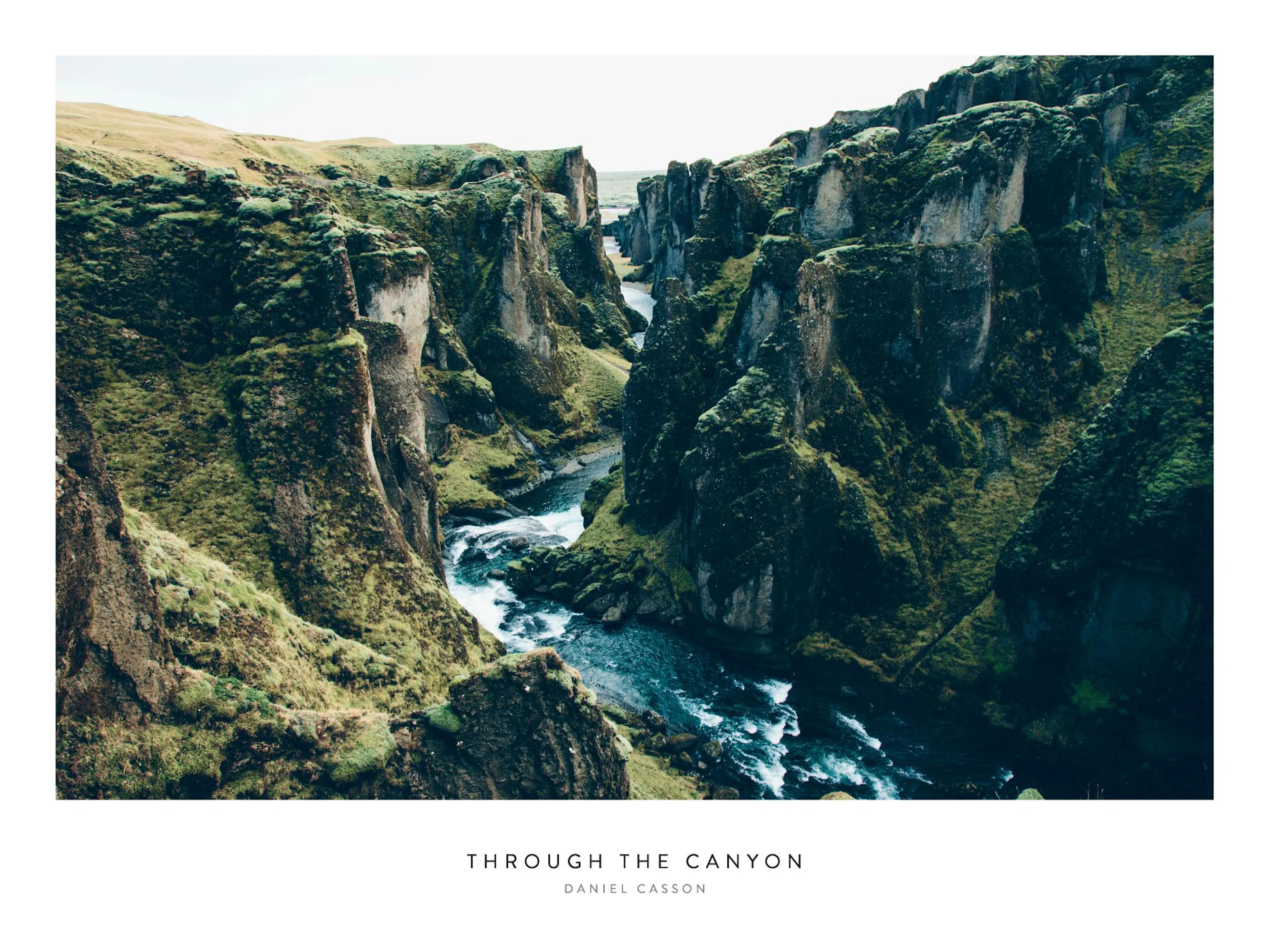Poster di un canyon profondo con ripide pareti rocciose coperte di muschio verde e un fiume che scorre.