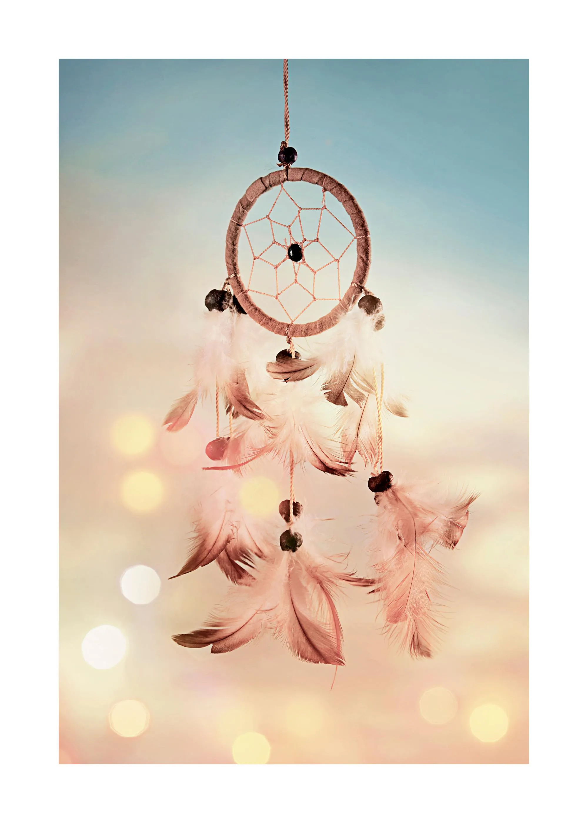 Een poster van een dromenvanger met bruine veren en kralen, hangend voor een wazige achtergrond met zachte bokeh-lichten.