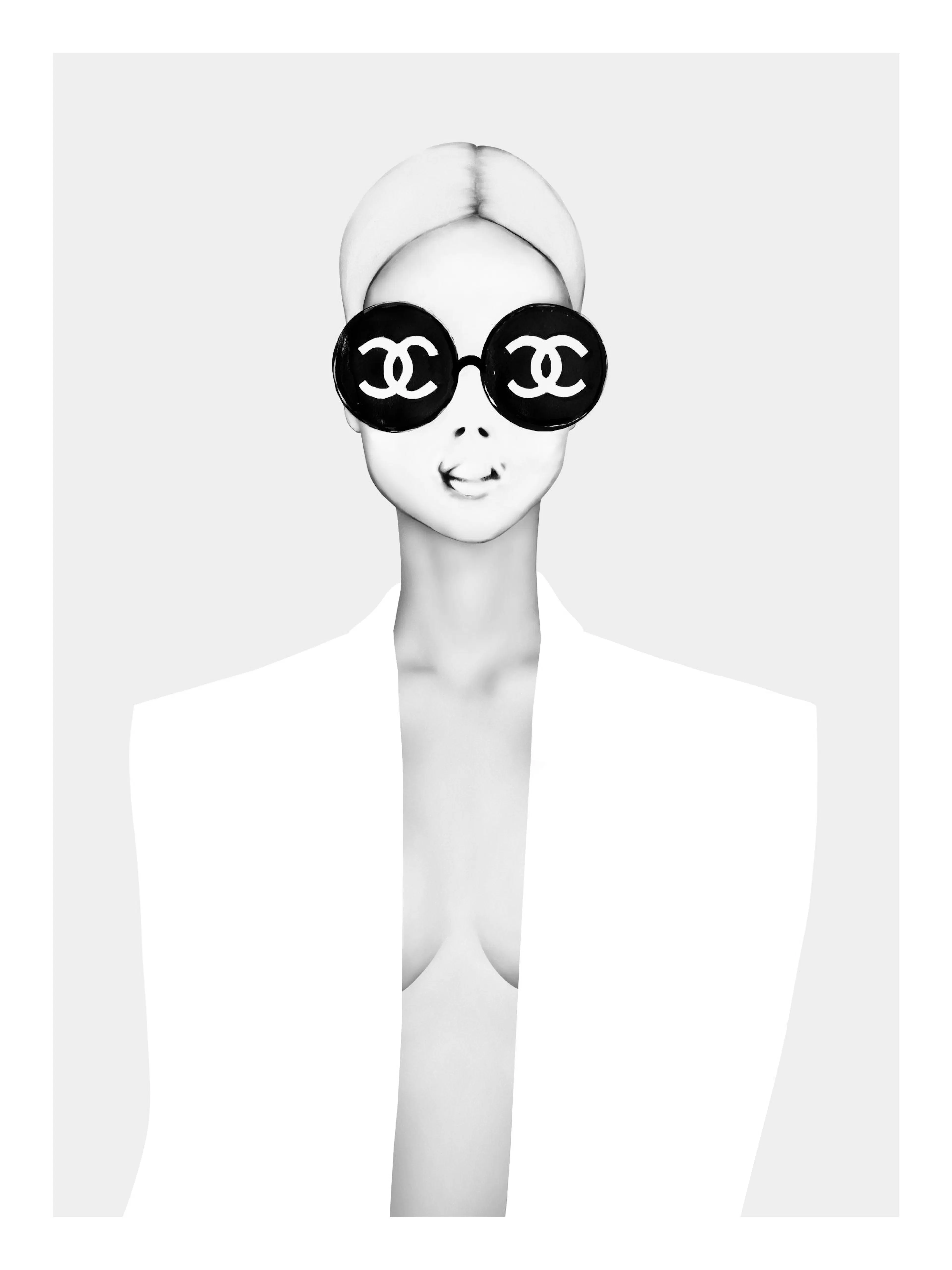 Póster de una mujer elegante en blanco y negro, con cabello rubio, y gafas de sol redondas con el logo de Chanel.