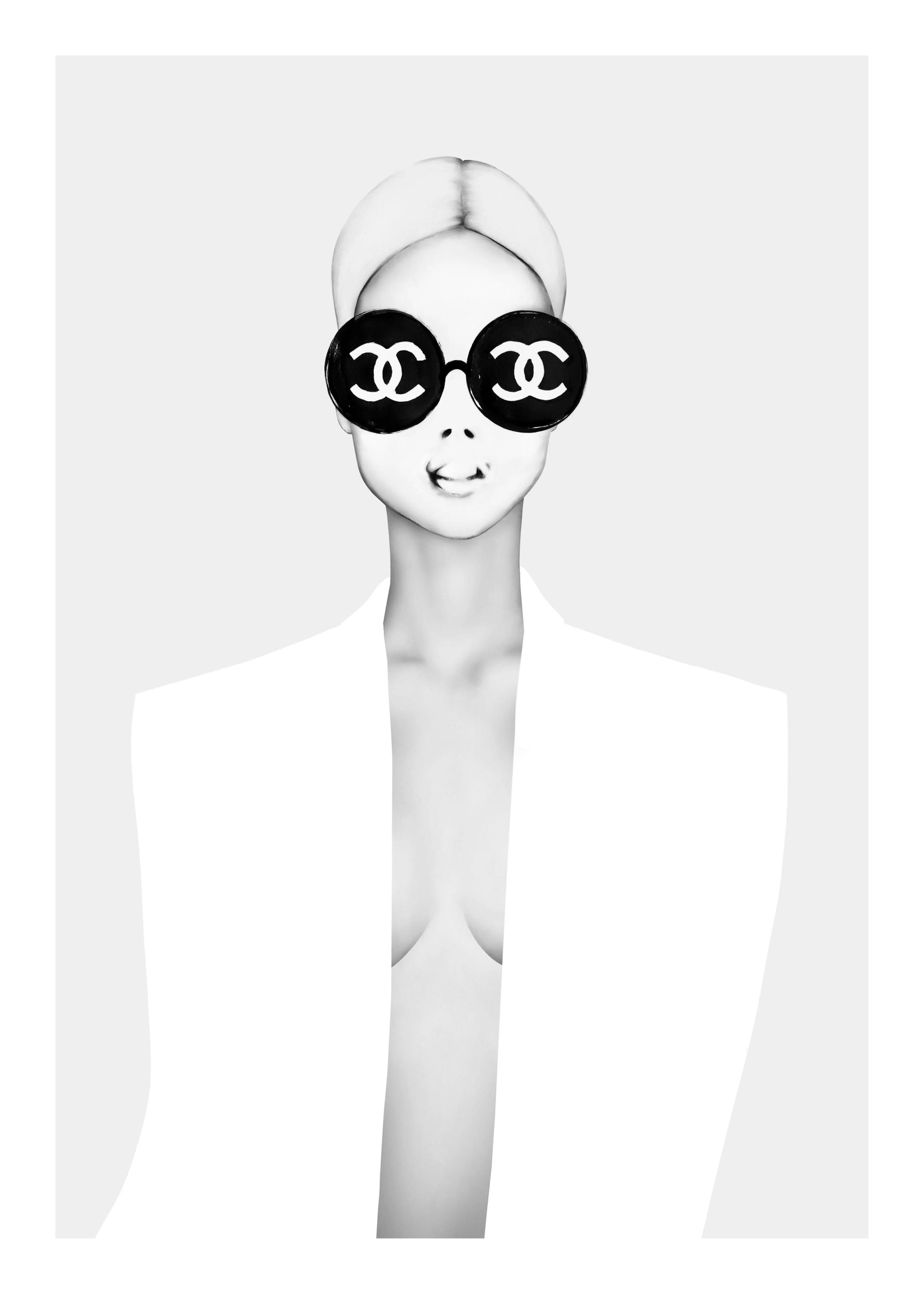 Mustavalkoinen juliste, jossa tyylikäs nainen valkoisessa bleiserissä ja Chanel-aurinkolaseissa.