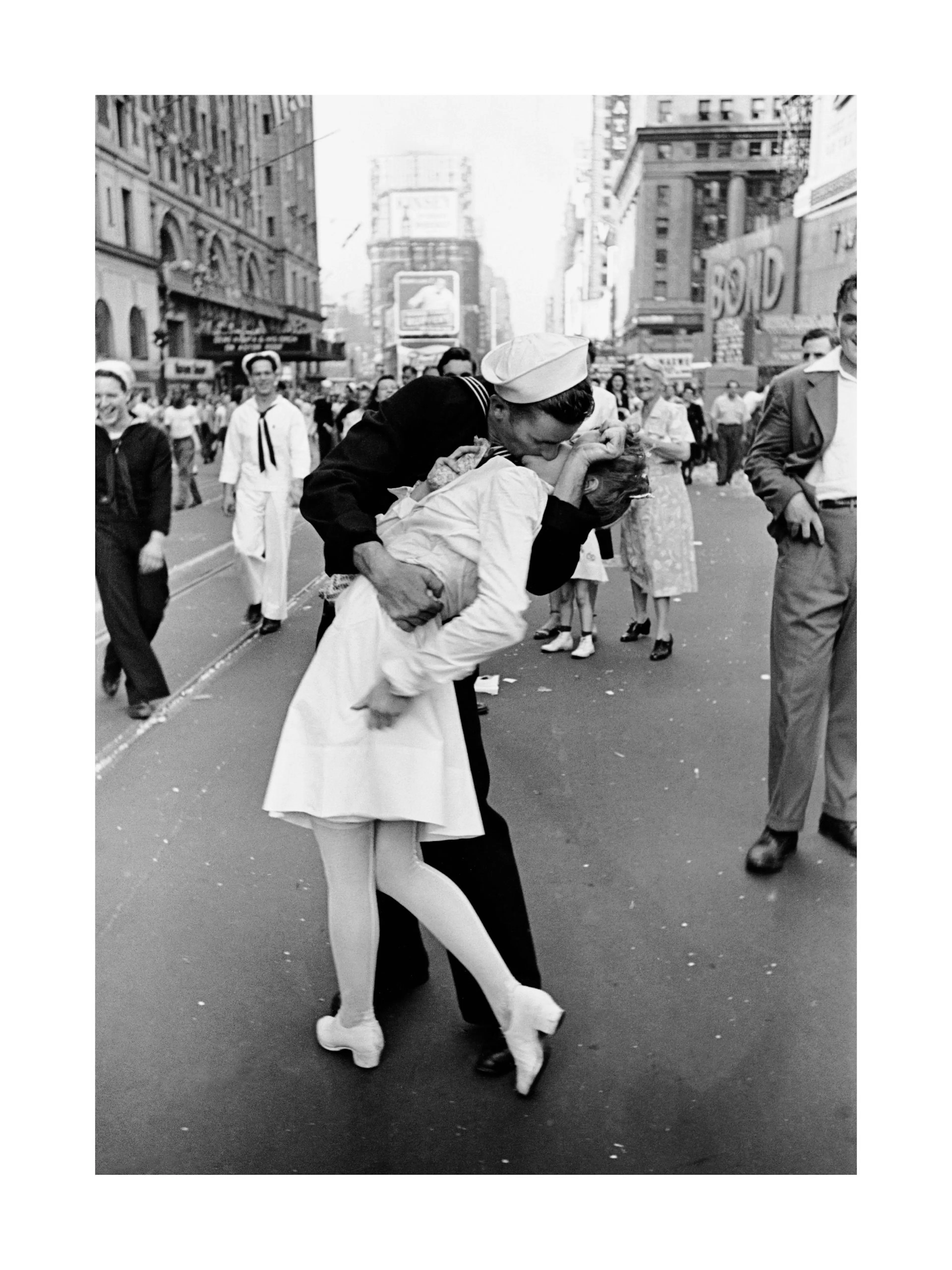 A poster of a black and white street scene featuring a sailor kissing a nurse, surrounded by pedestrians.