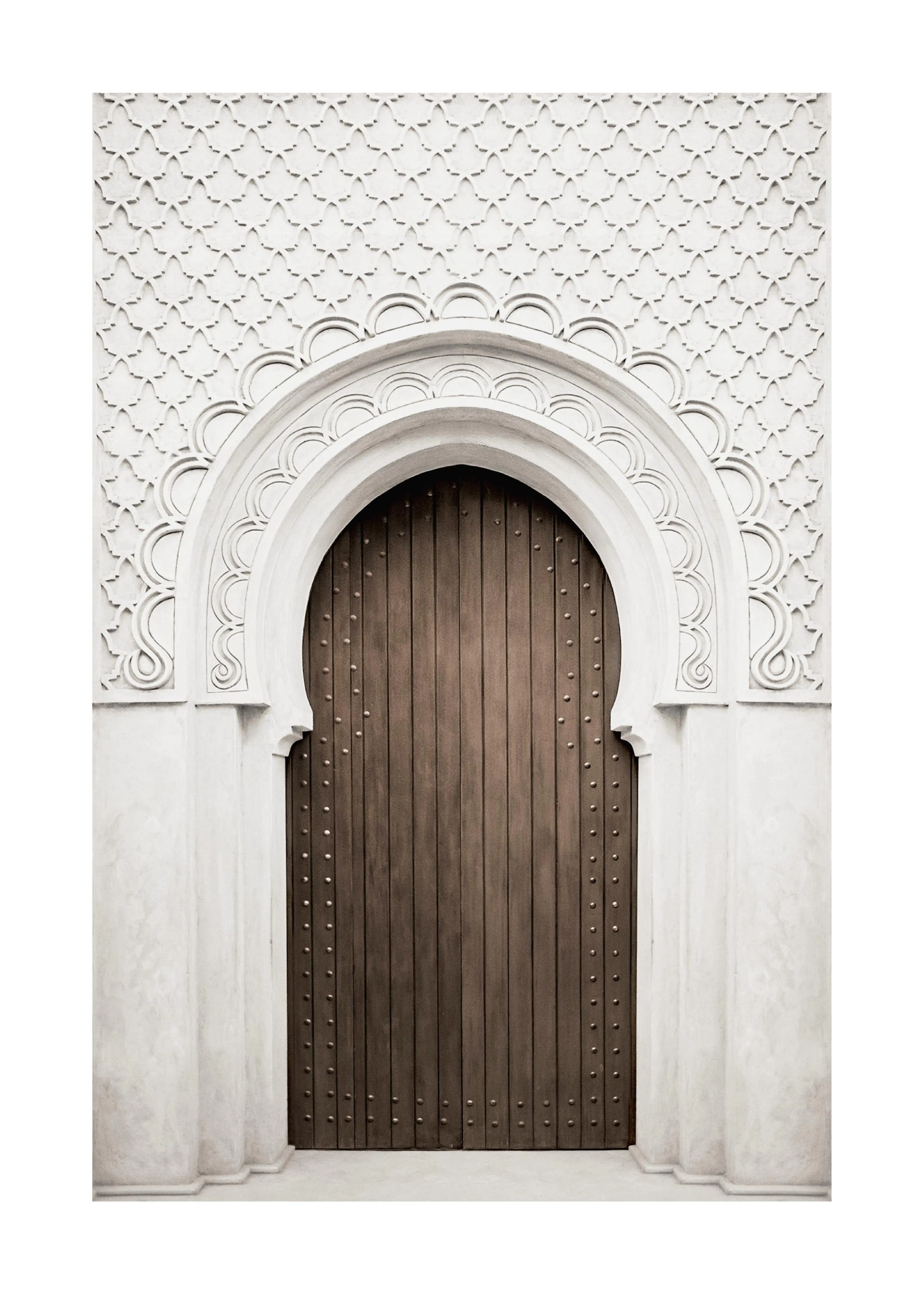 En poster av en marockansk dörr med intrikata detaljer i vitt och en mörkbrun, nitad trädörr.