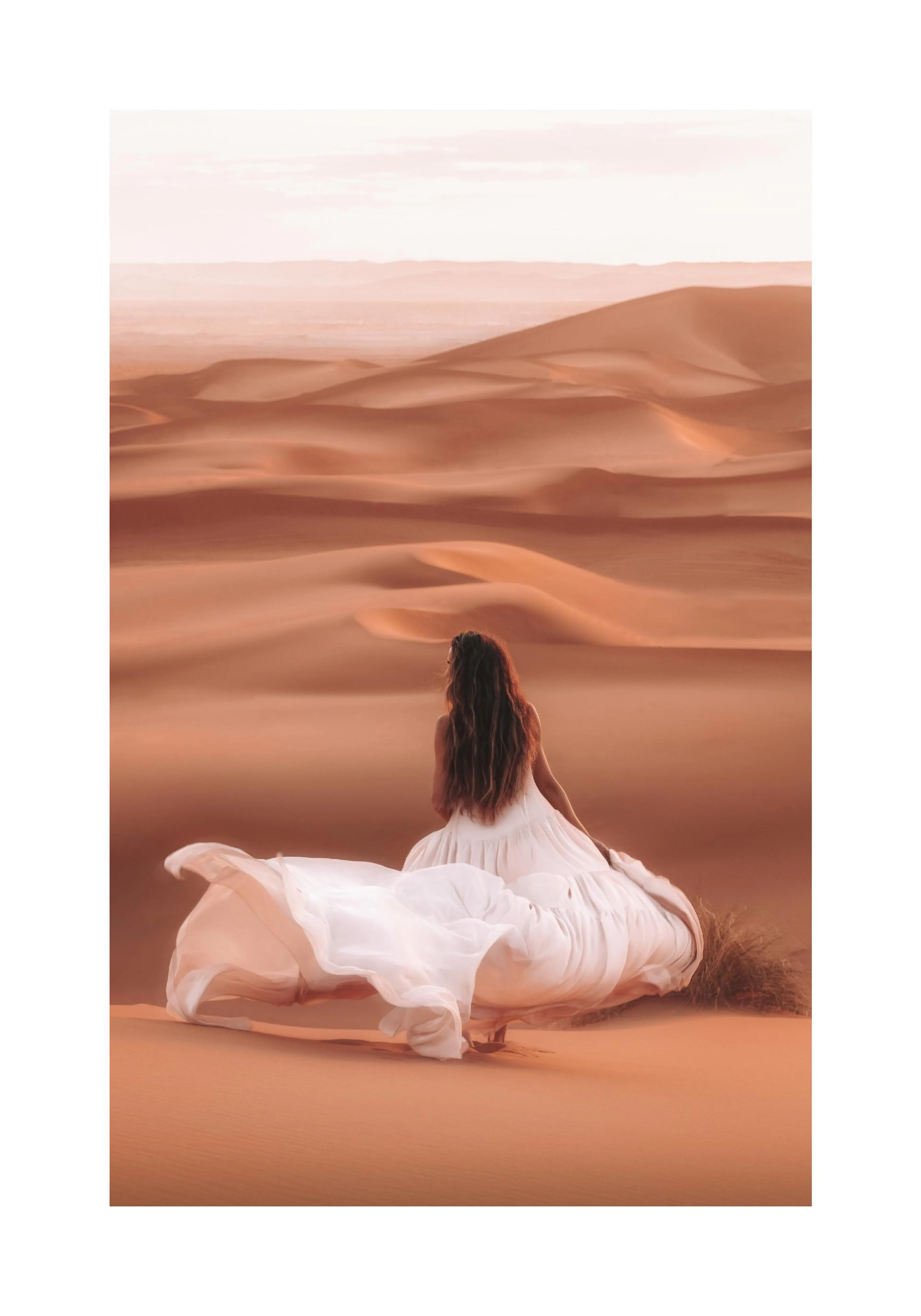 A poster featuring a woman in a flowing white dress sitting on an orange desert dune, looking out at more dunes.