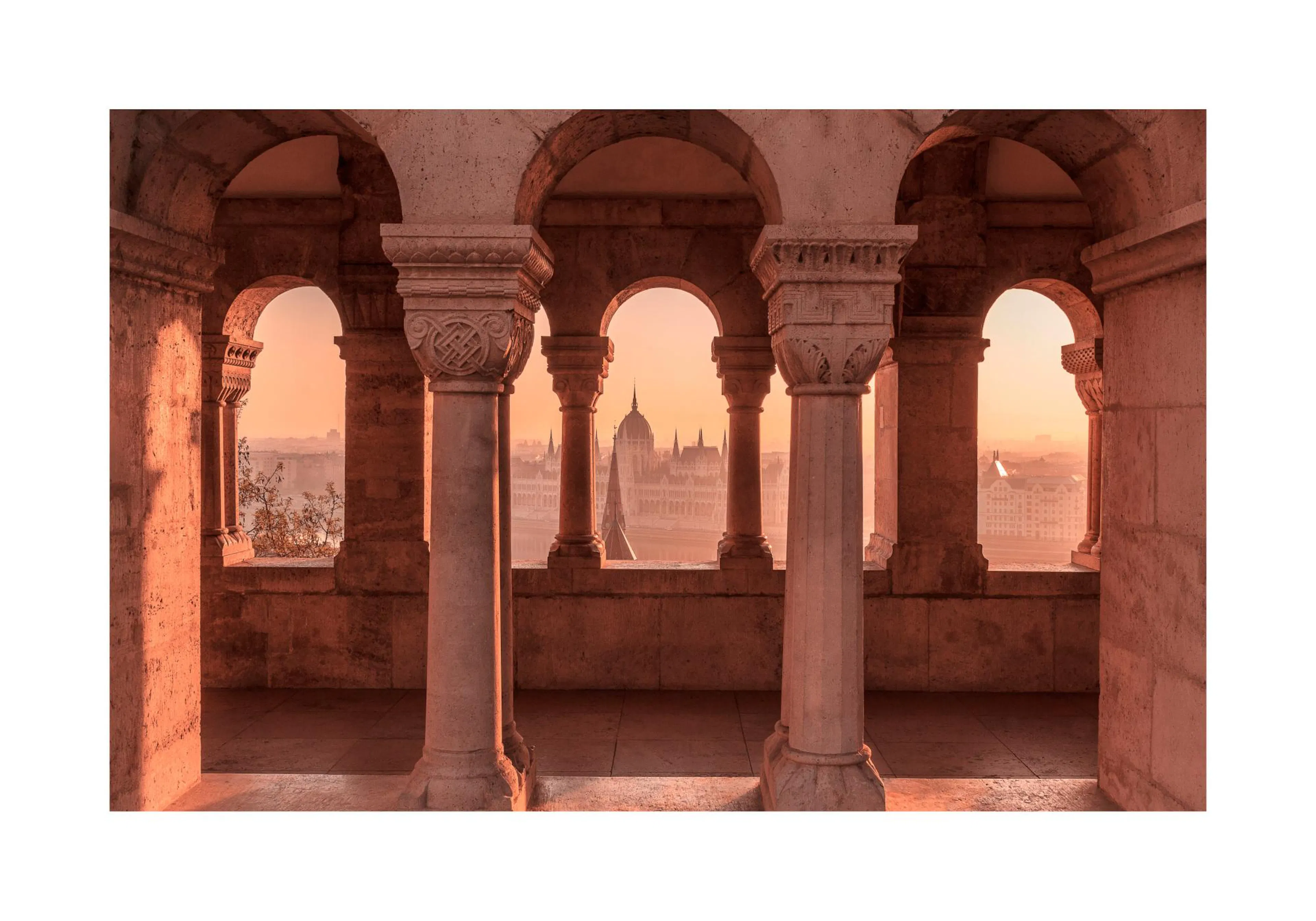 Poster du parlement de Budapest vu à travers les arcs de pierre du Bastion des Pêcheurs au lever du soleil.
