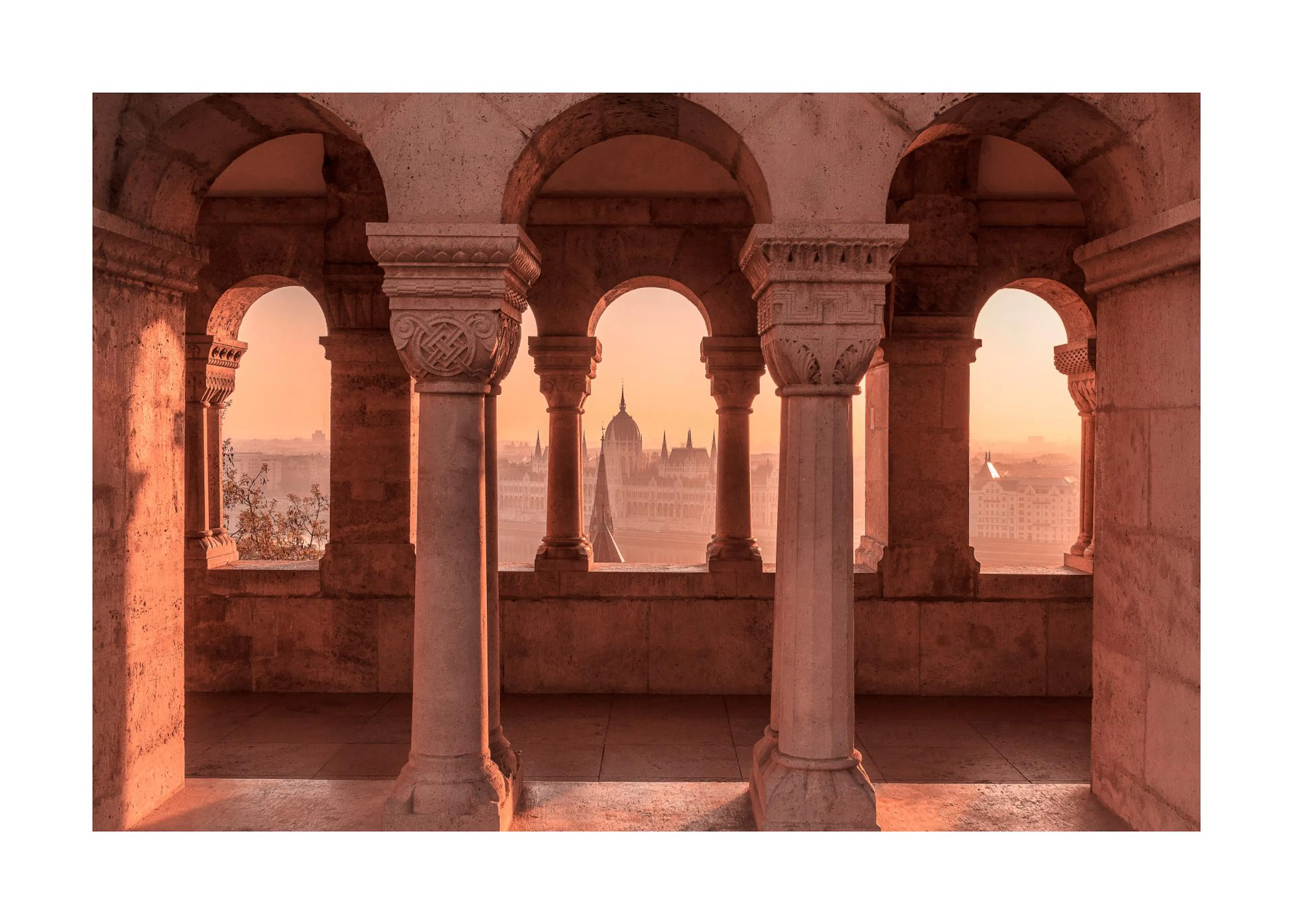 A poster depicting a view through ornate stone arches and columns, revealing the Hungarian Parliament Building at sunset.