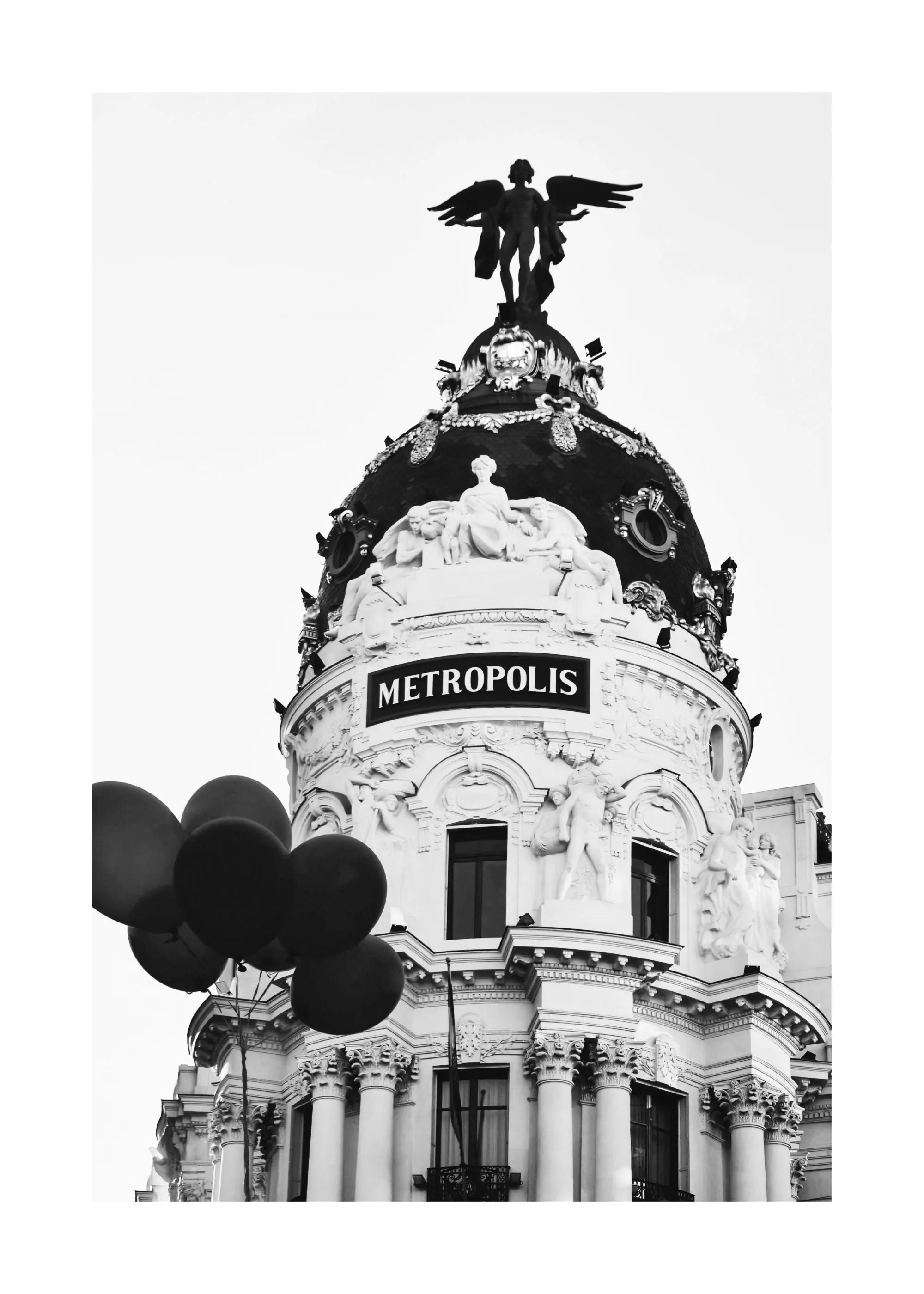 Un poster en noir et blanc de lédifice Metropolis à Madrid avec des ballons foncés, mettant en valeur sa coupole et sa statue ai