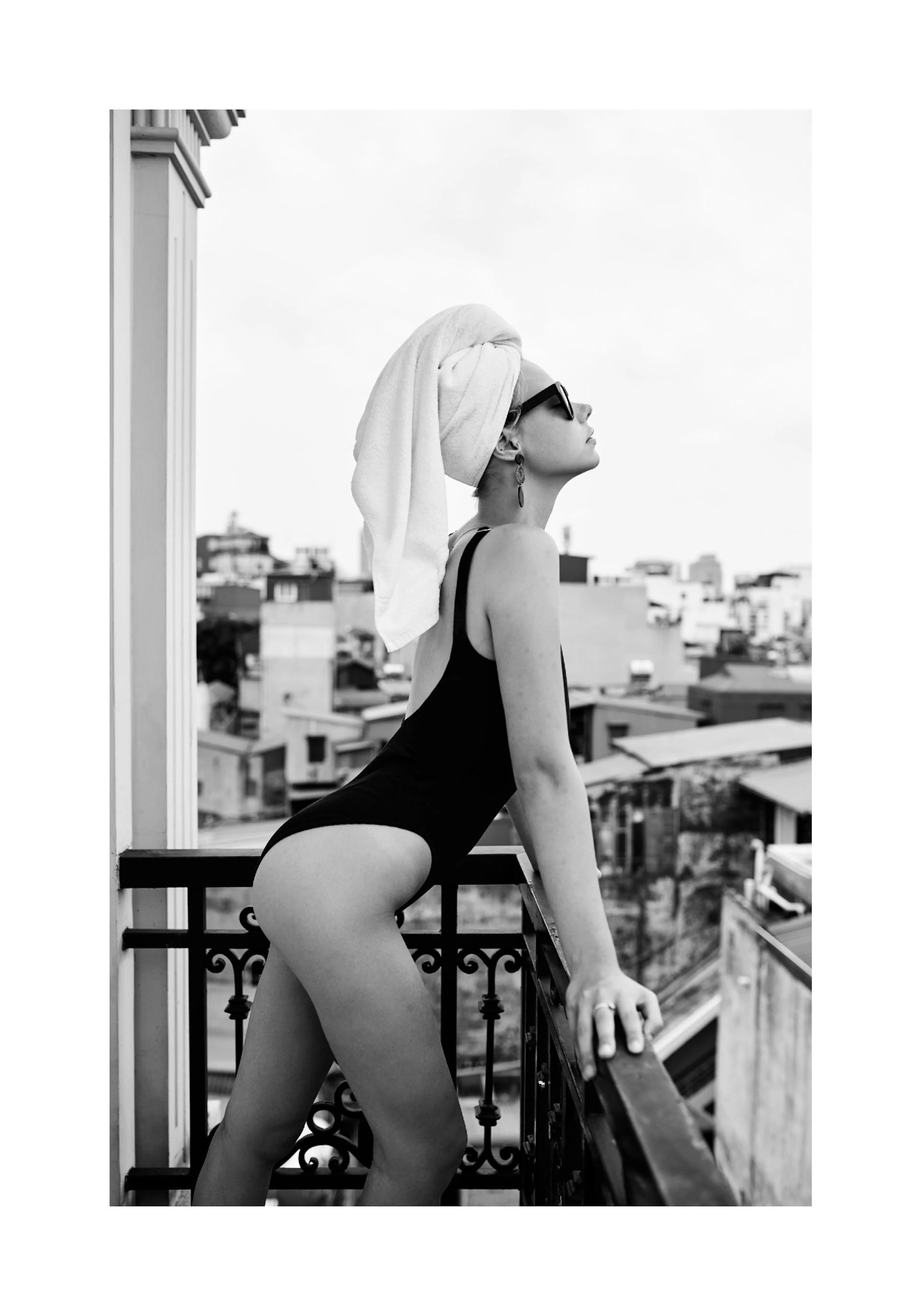 Poster noir et blanc dune femme en maillot de bain et serviette sur la tête, sur un balcon.