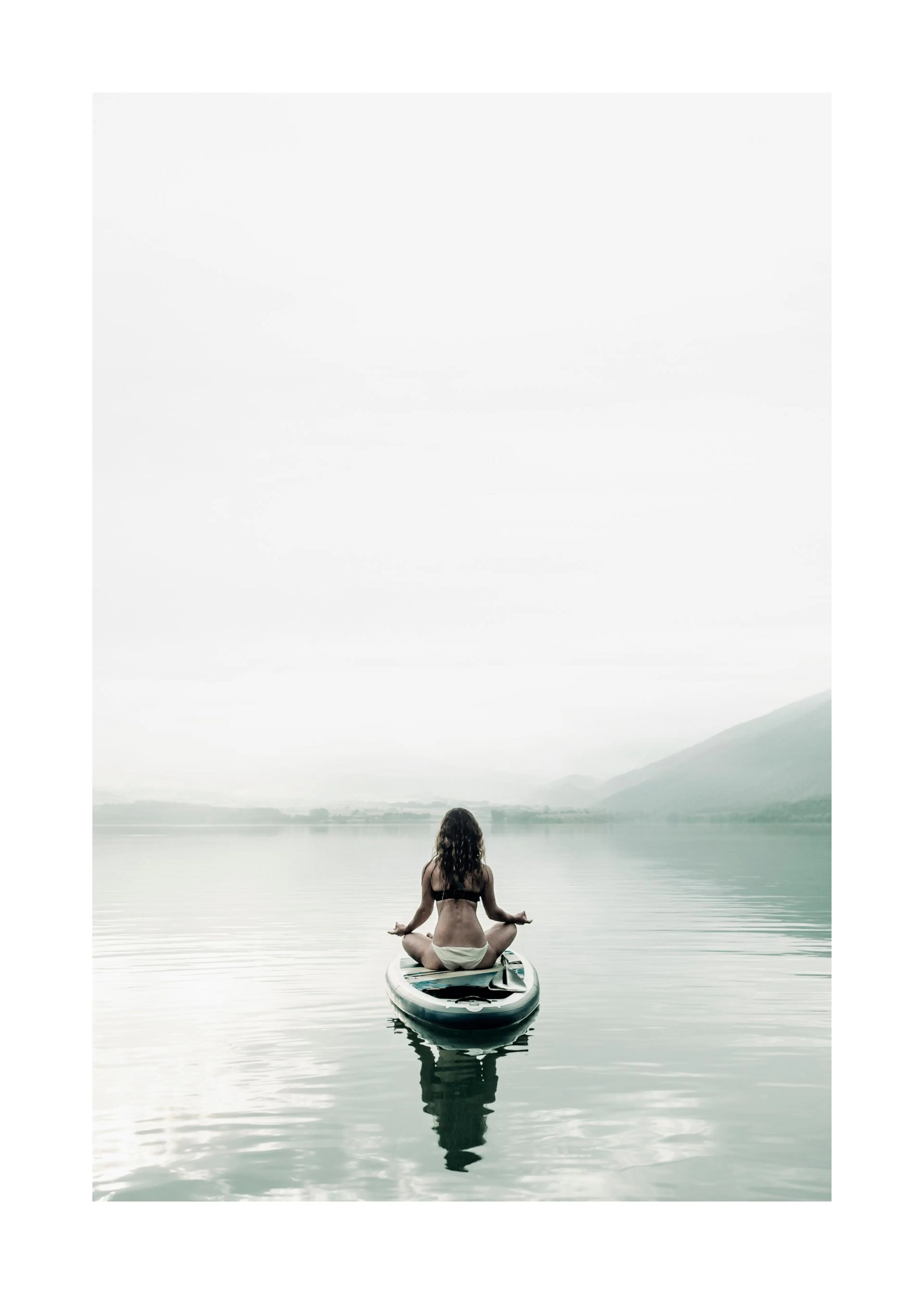 Un poster dune femme en bikini méditant sur une planche à pagaie au milieu dun lac, montagnes en arrière-plan.