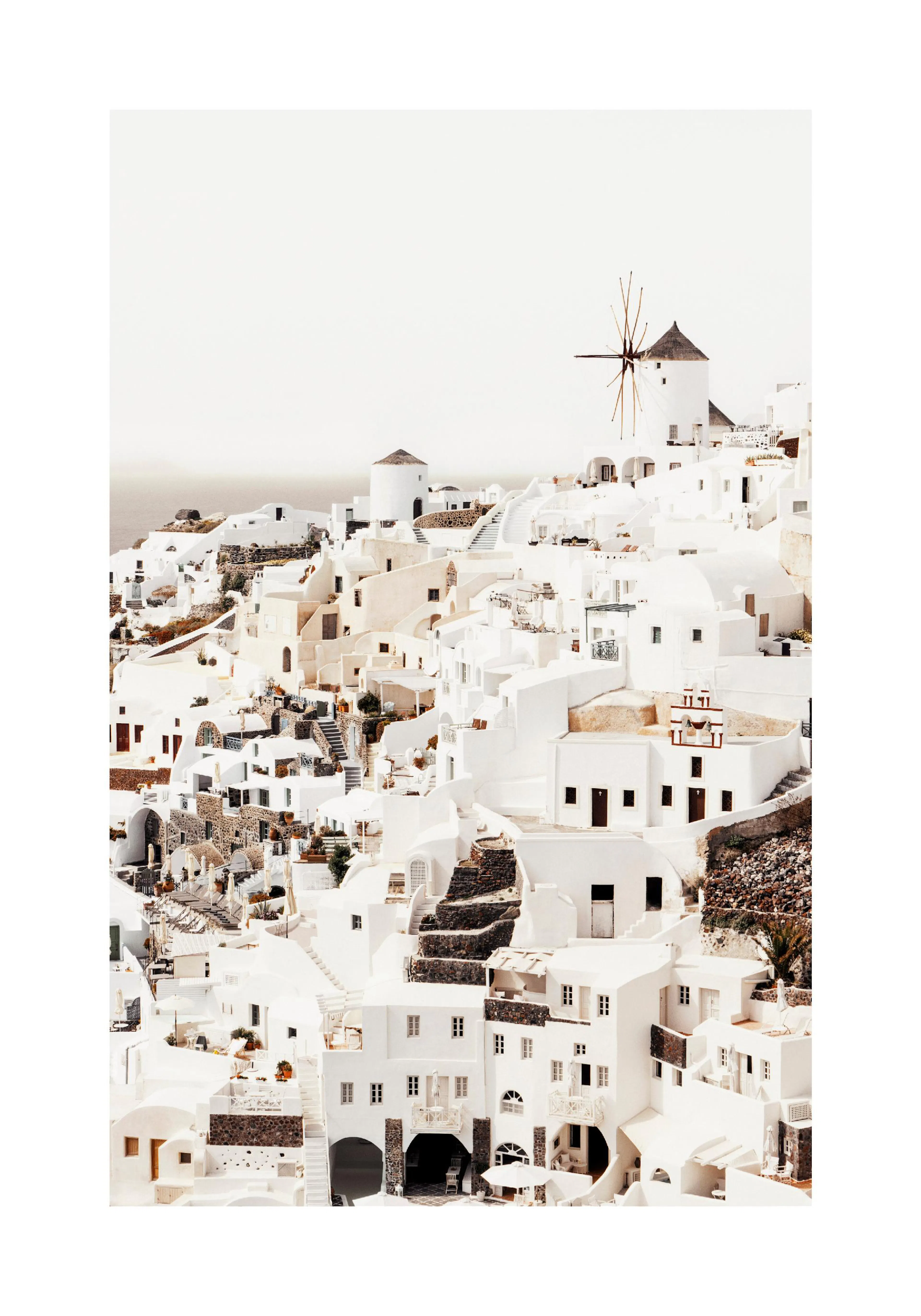 A poster featuring a beautiful landscape of white buildings and windmills on a hill overlooking the sea in Santorini, Greece.