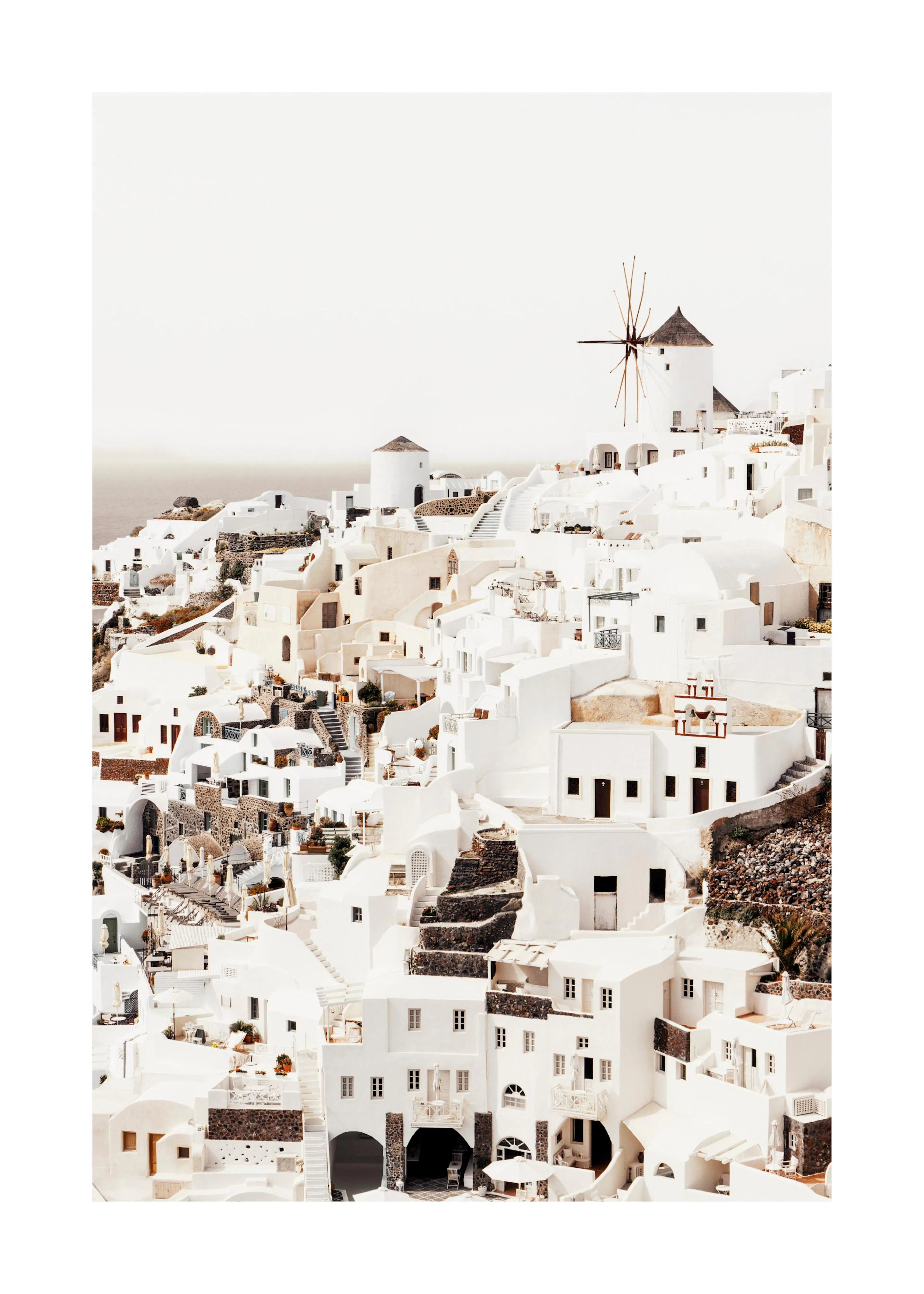 A poster featuring a beautiful landscape of white buildings and windmills on a hill overlooking the sea in Santorini, Greece.