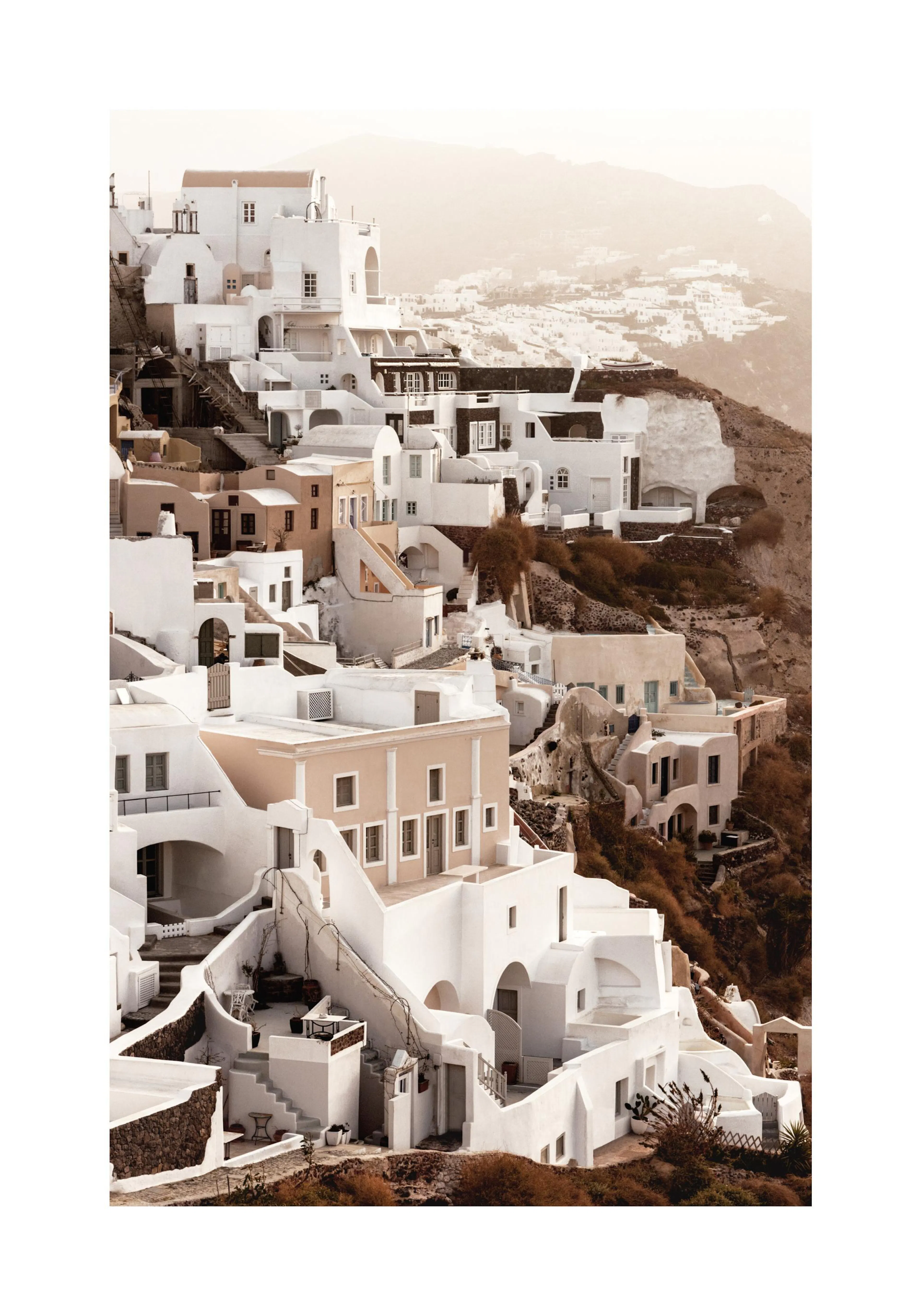 A poster featuring a hillside village of white and beige buildings with a hazy, warm-toned sky and mountains in the background.