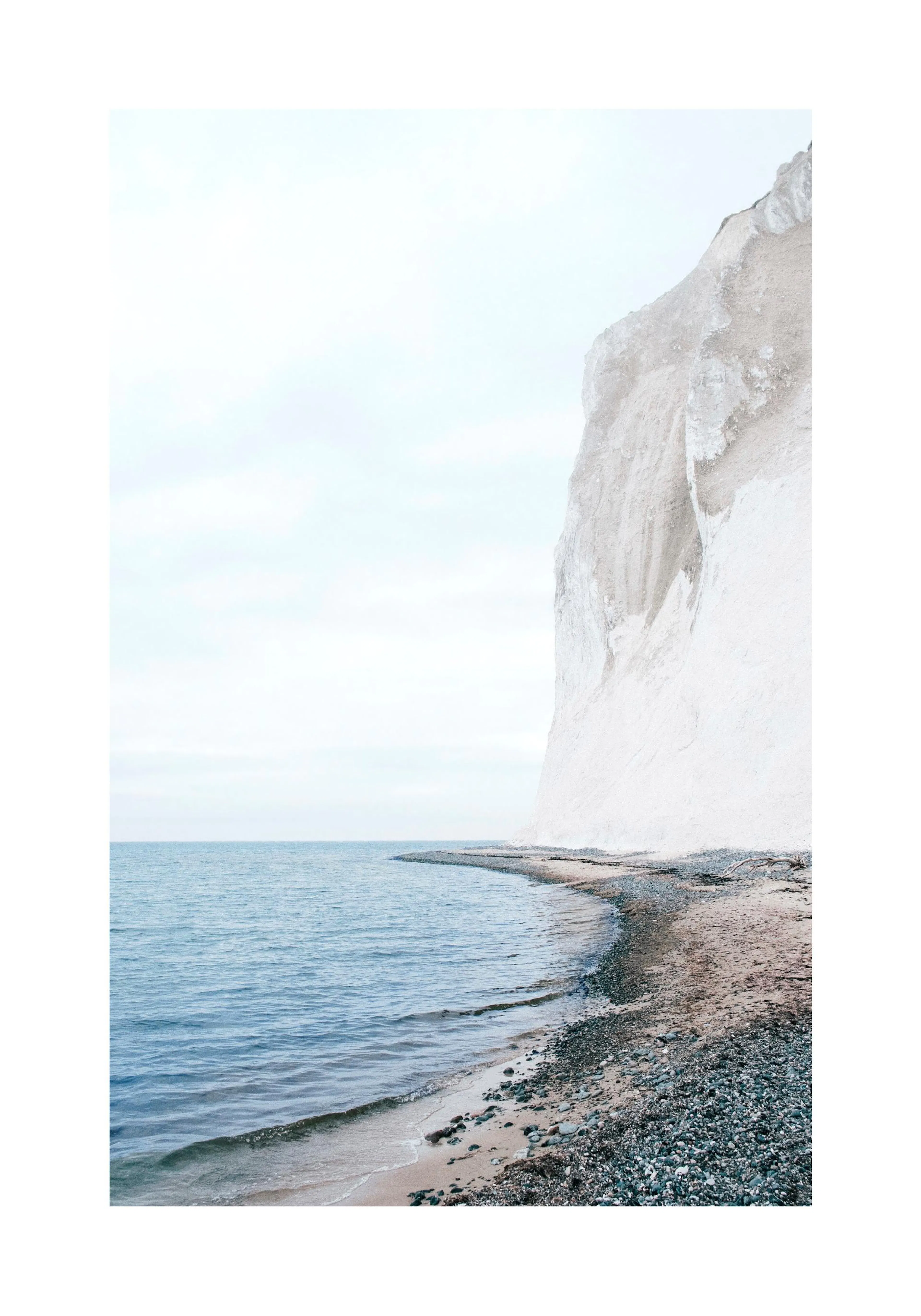 A poster featuring a high white cliff meeting a sandy and rocky beach and calm blue water under a bright sky.