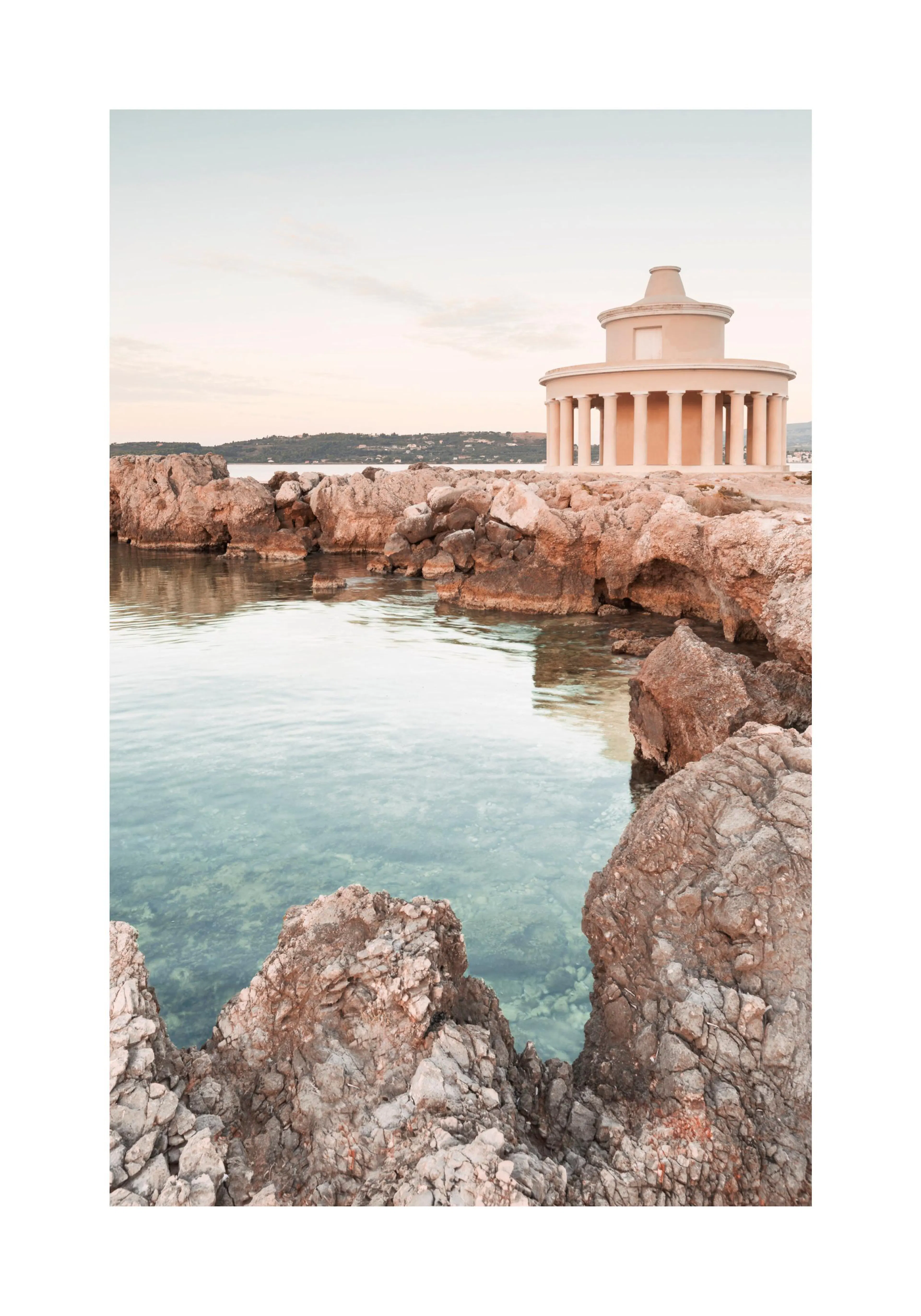 A poster featuring a round, ancient Greek-inspired building with columns on a rocky coastline next to clear blue water.
