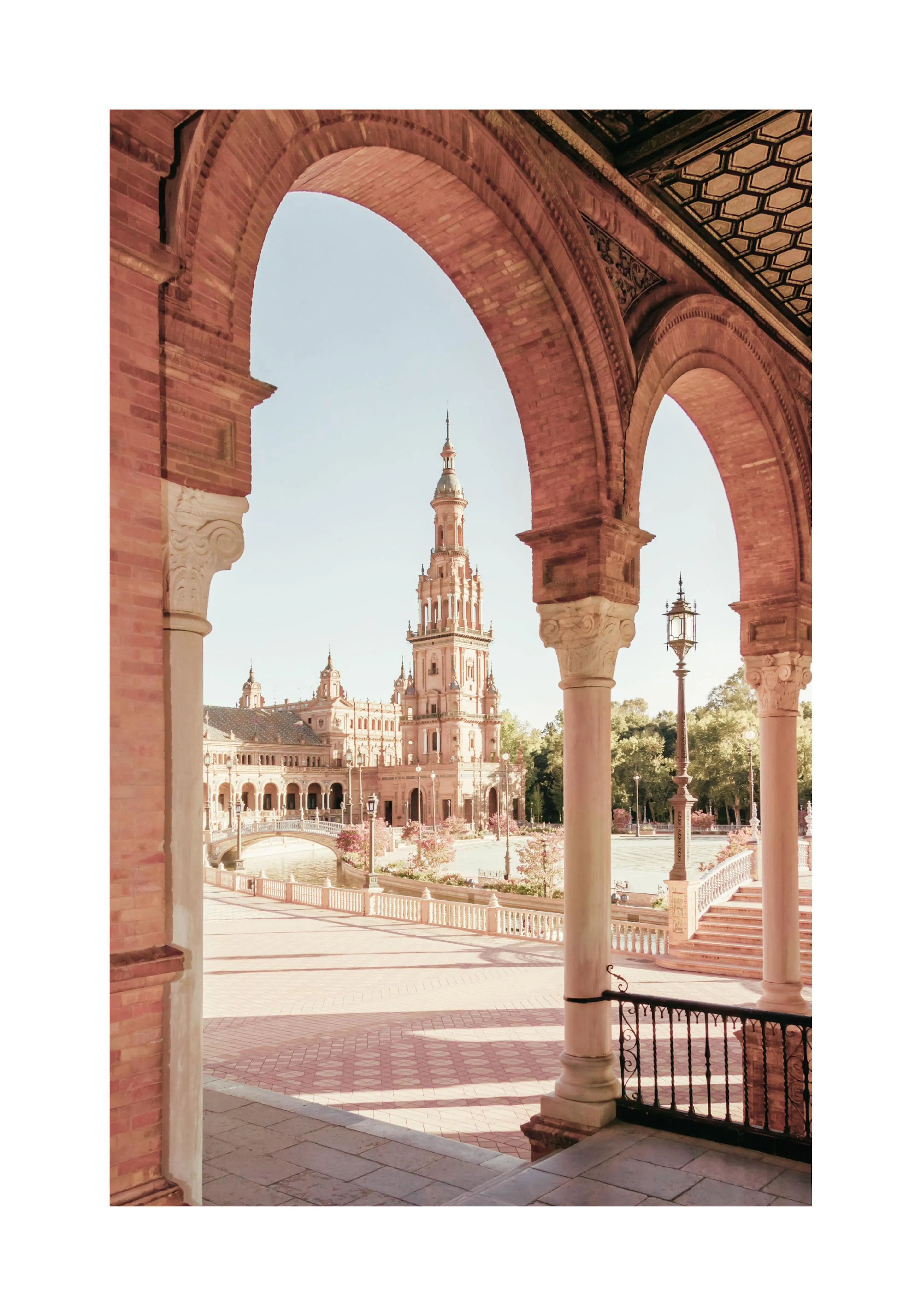 A poster featuring a grand Spanish archway framing a historical building with a tall tower and a bridge over water.