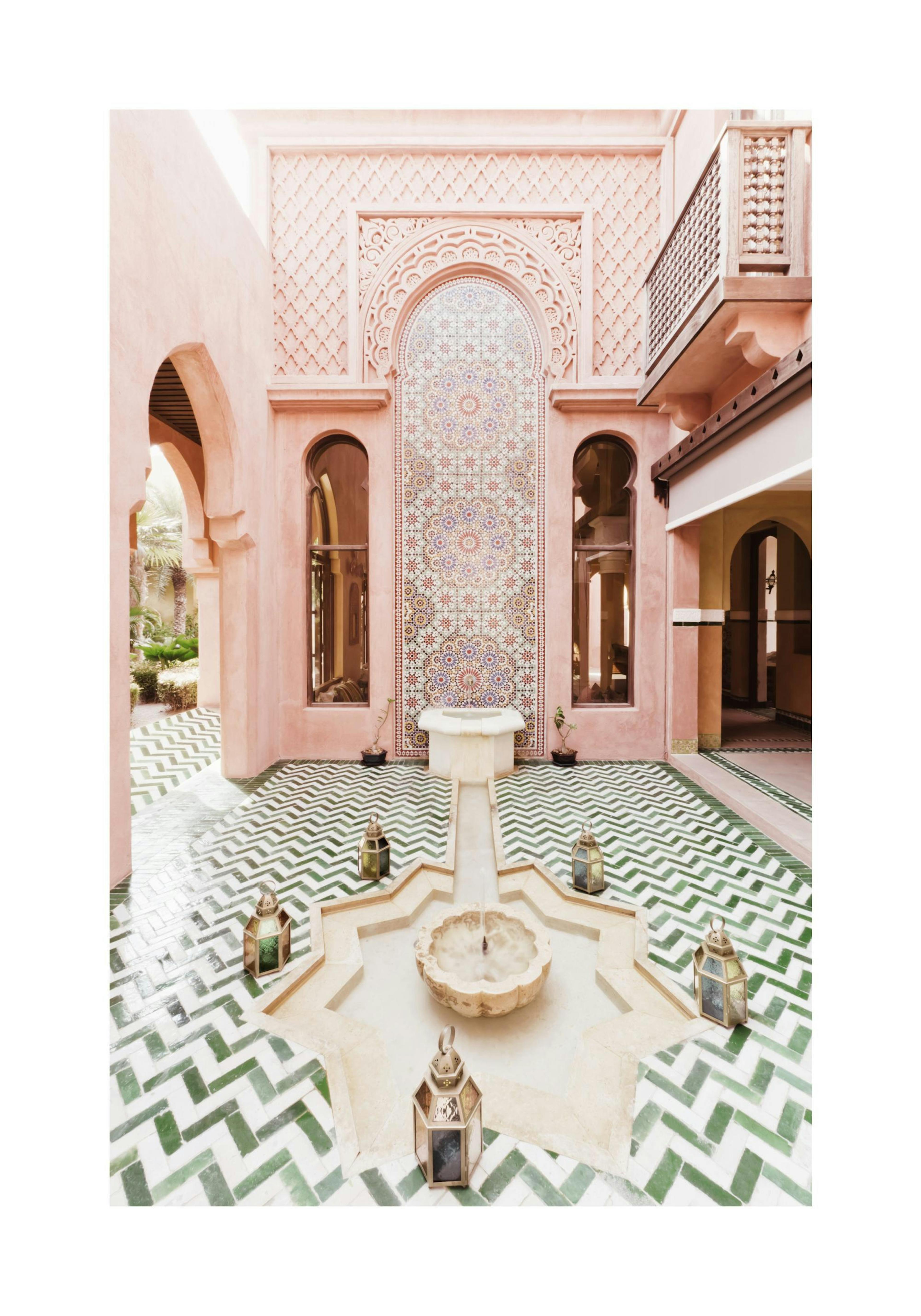 모로코풍 건축물의 분수가 있는 마당을 담은 poster. 분수 주위의 헤링본 녹색 타일 바닥과 분홍빛 벽이 특징입니다.