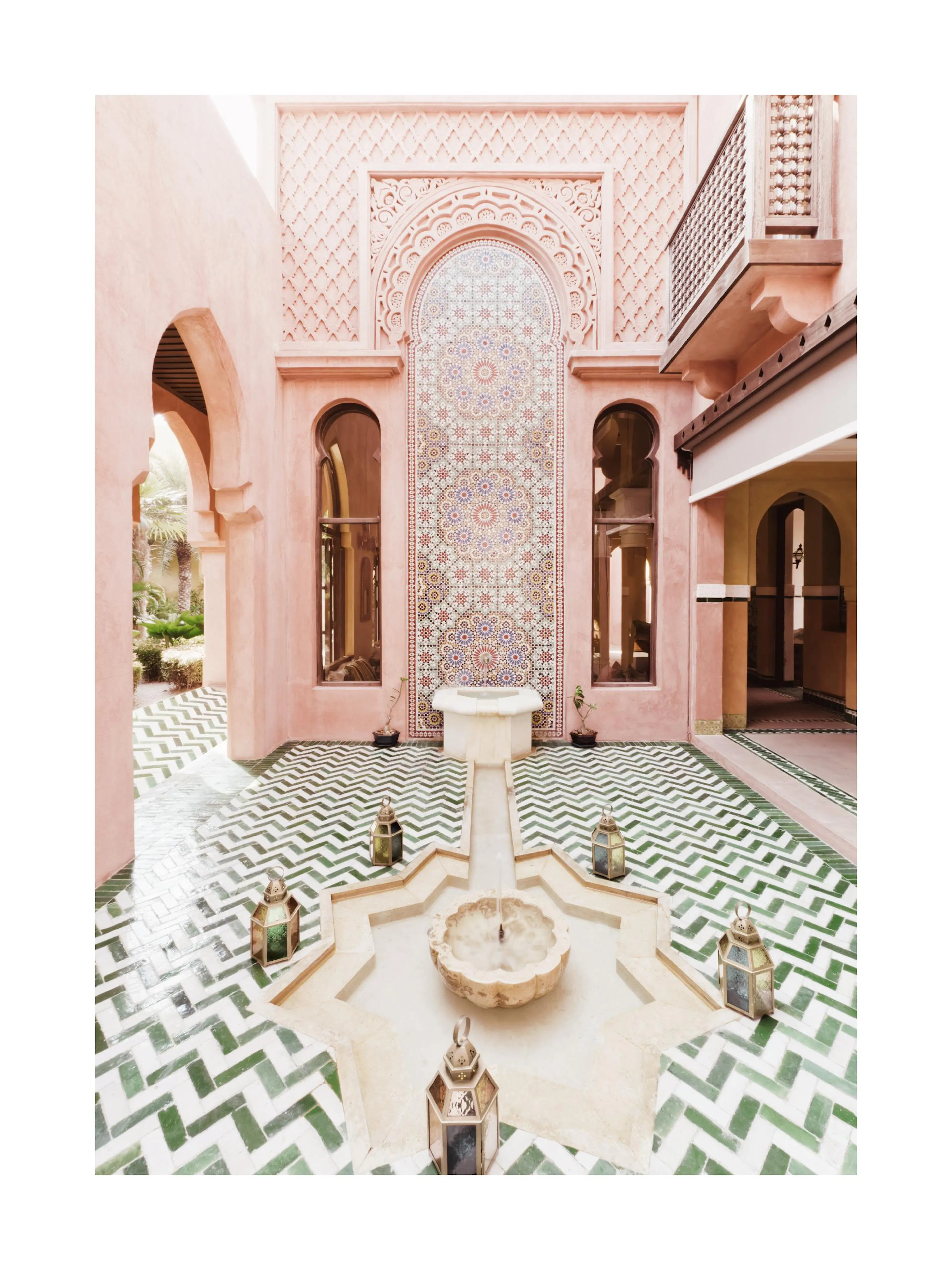 A poster featuring a Moroccan courtyard with pink plastered walls, green and white mosaic tile patterns, and a central fountain.