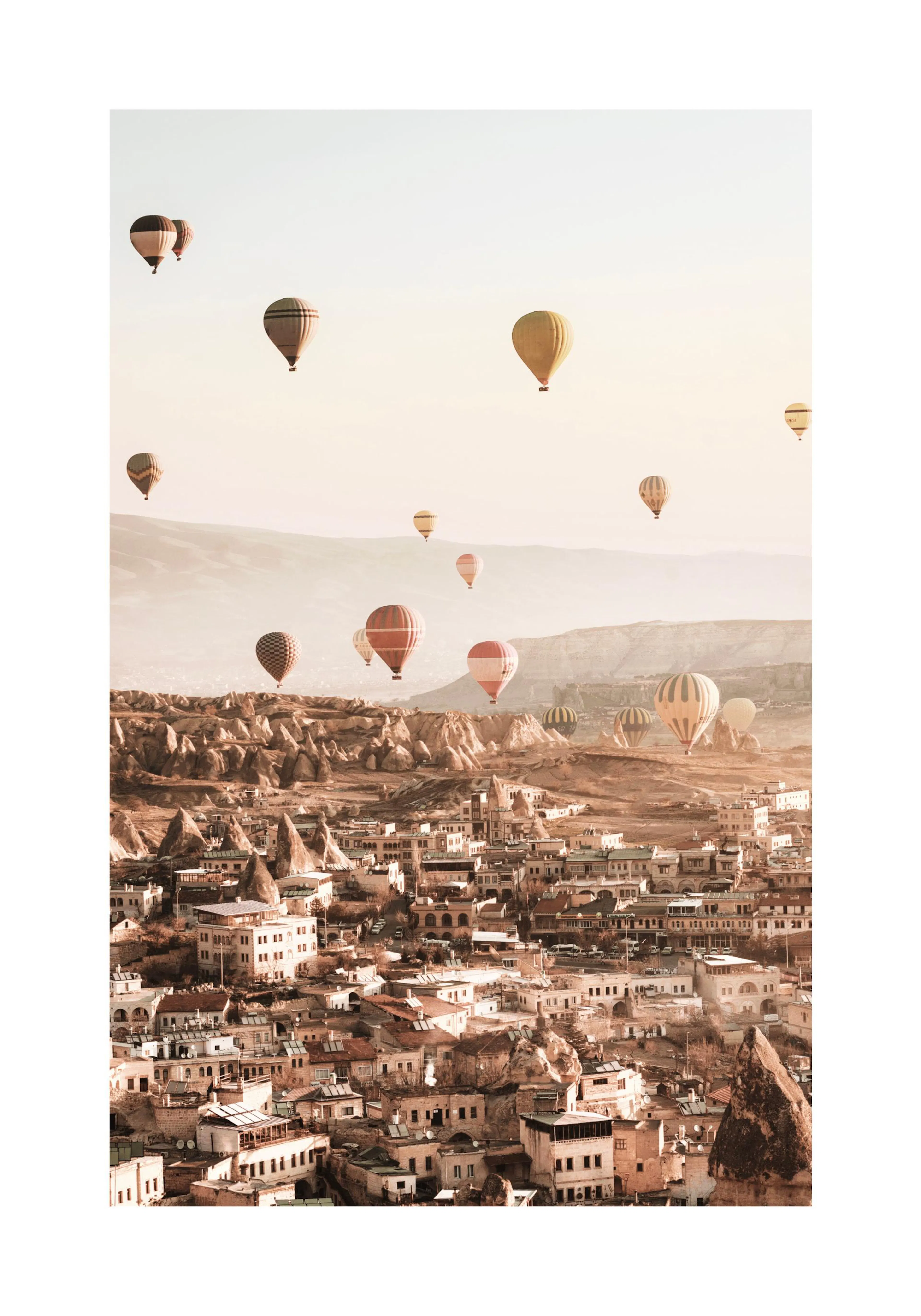 Poster: Warme Ansicht einer Stadt in Kappadokien mit vielen bunten Heißluftballons am Himmel.