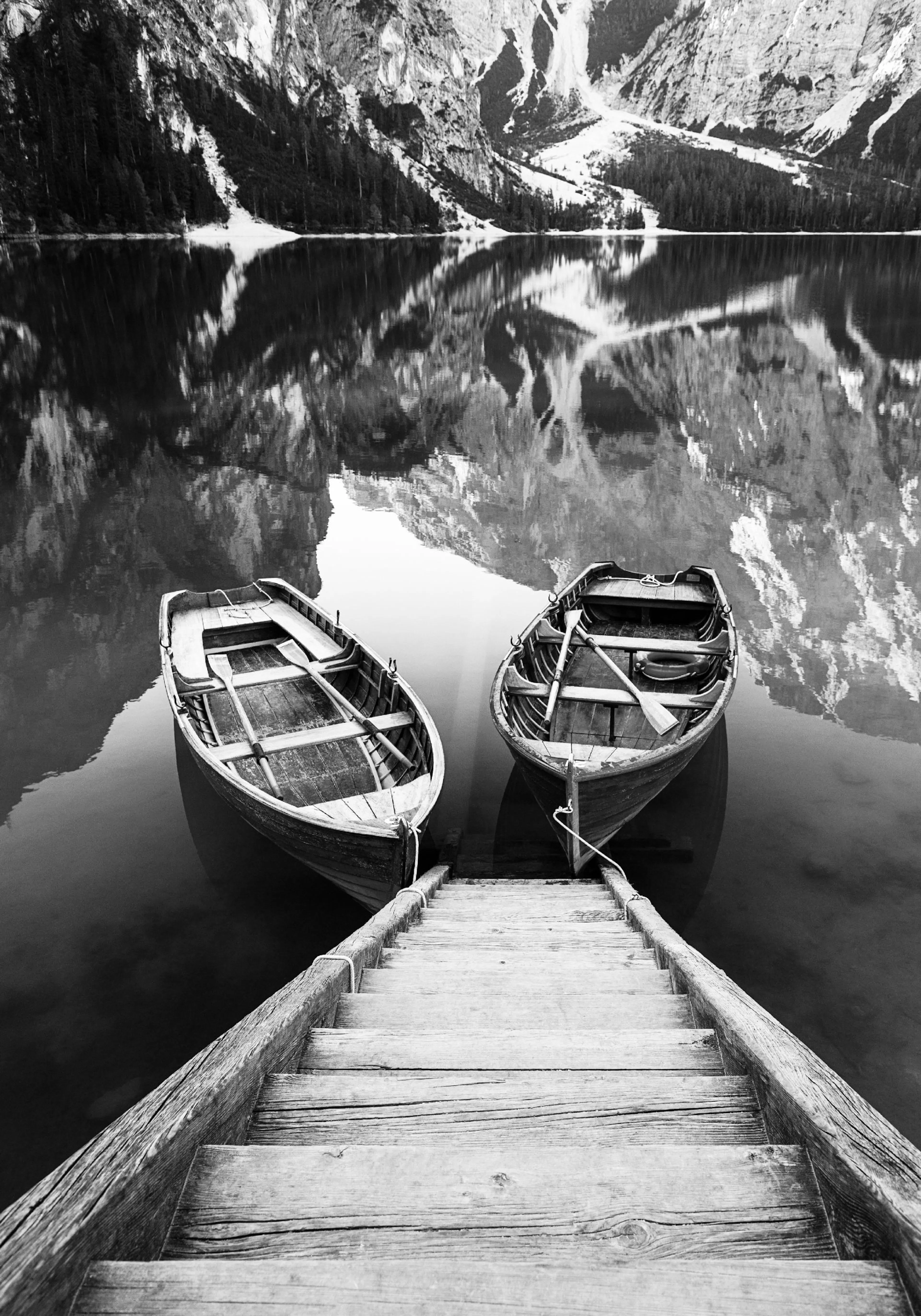Poster noir et blanc de deux barques en bois sur un lac reflétant des montagnes.