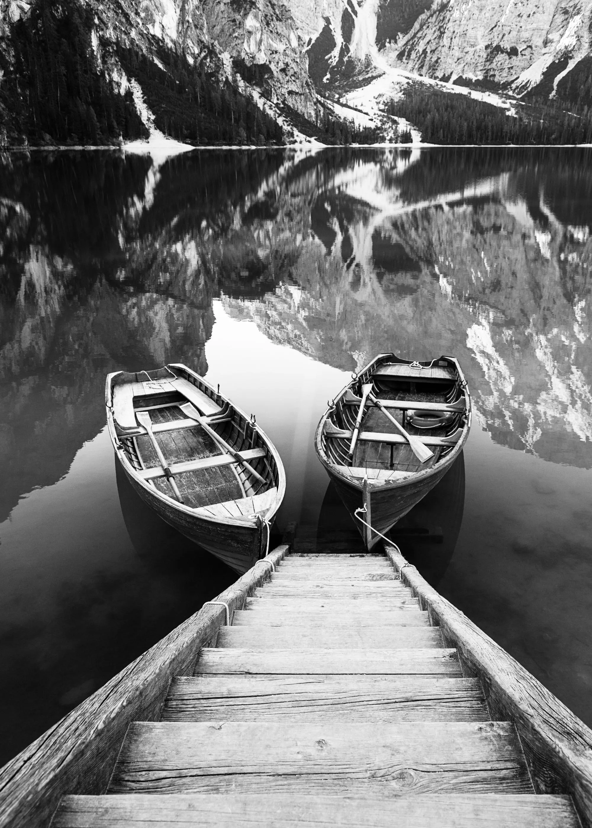 Poster noir et blanc de deux barques en bois sur un lac reflétant des montagnes.