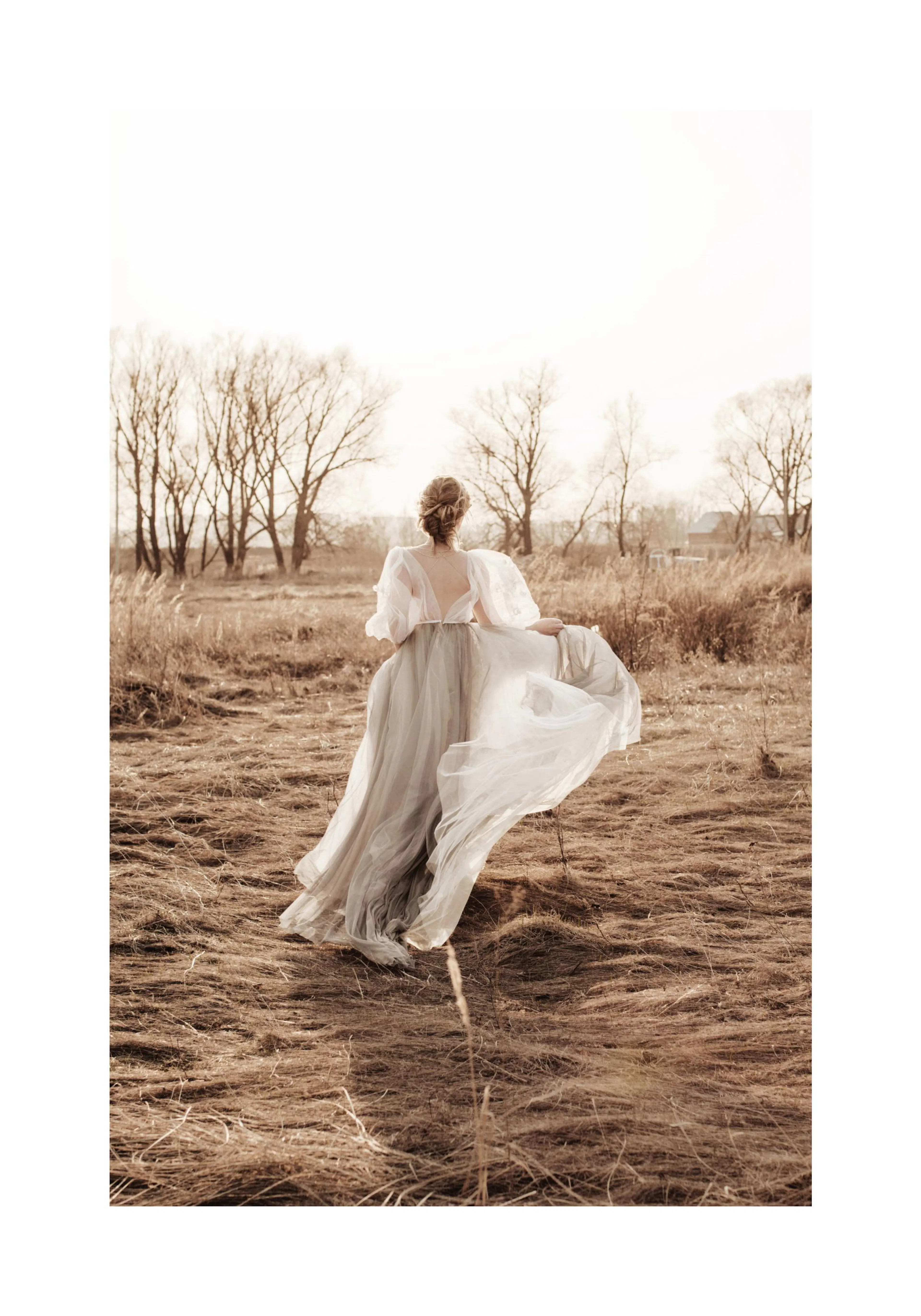 A poster depicting a woman in a flowing white gown walking through a dry, grassy field with bare trees in the background.