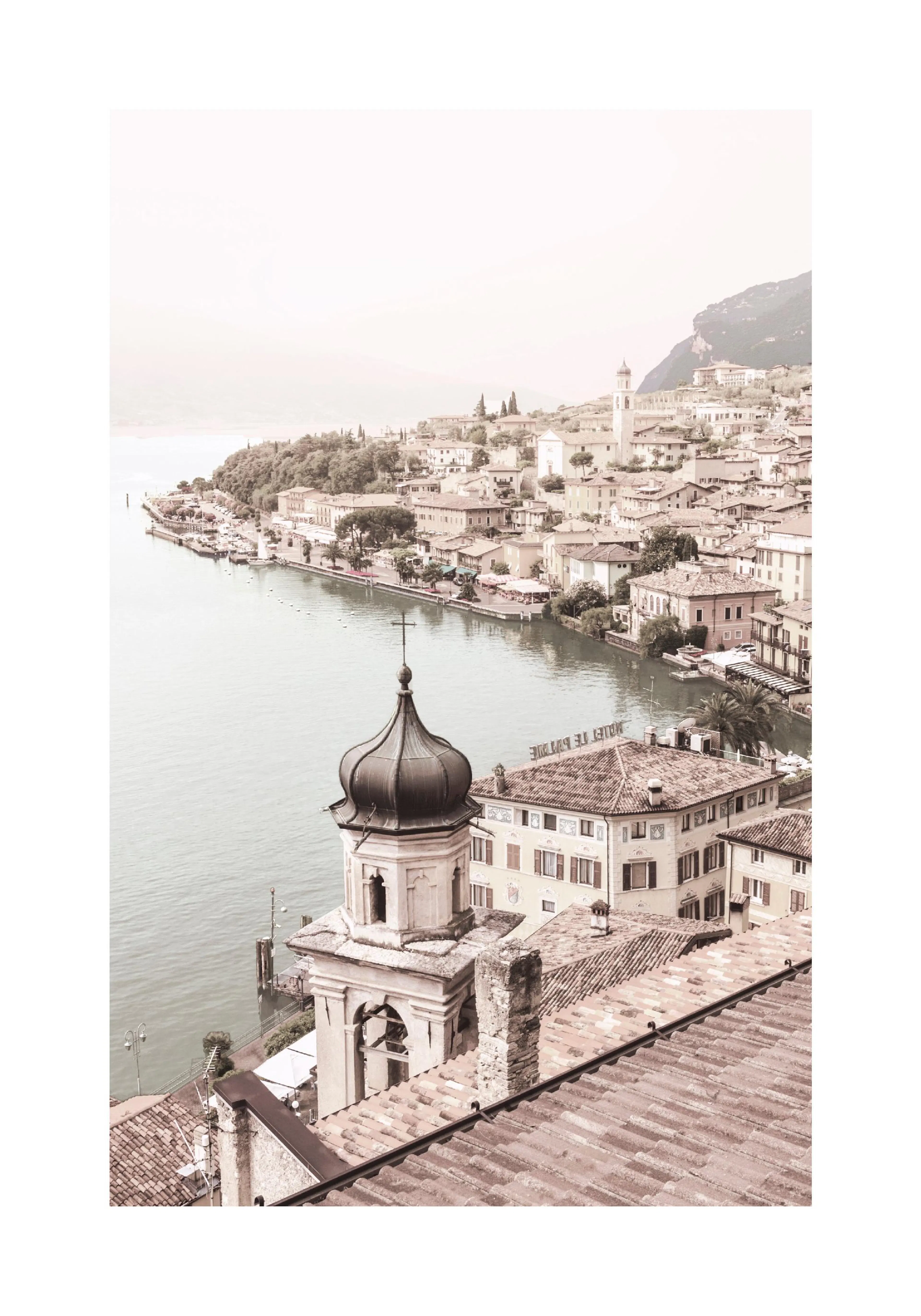 A poster featuring a high-angle view of a coastal town with red-tiled roofs, a large body of water, and mountains in the distanc