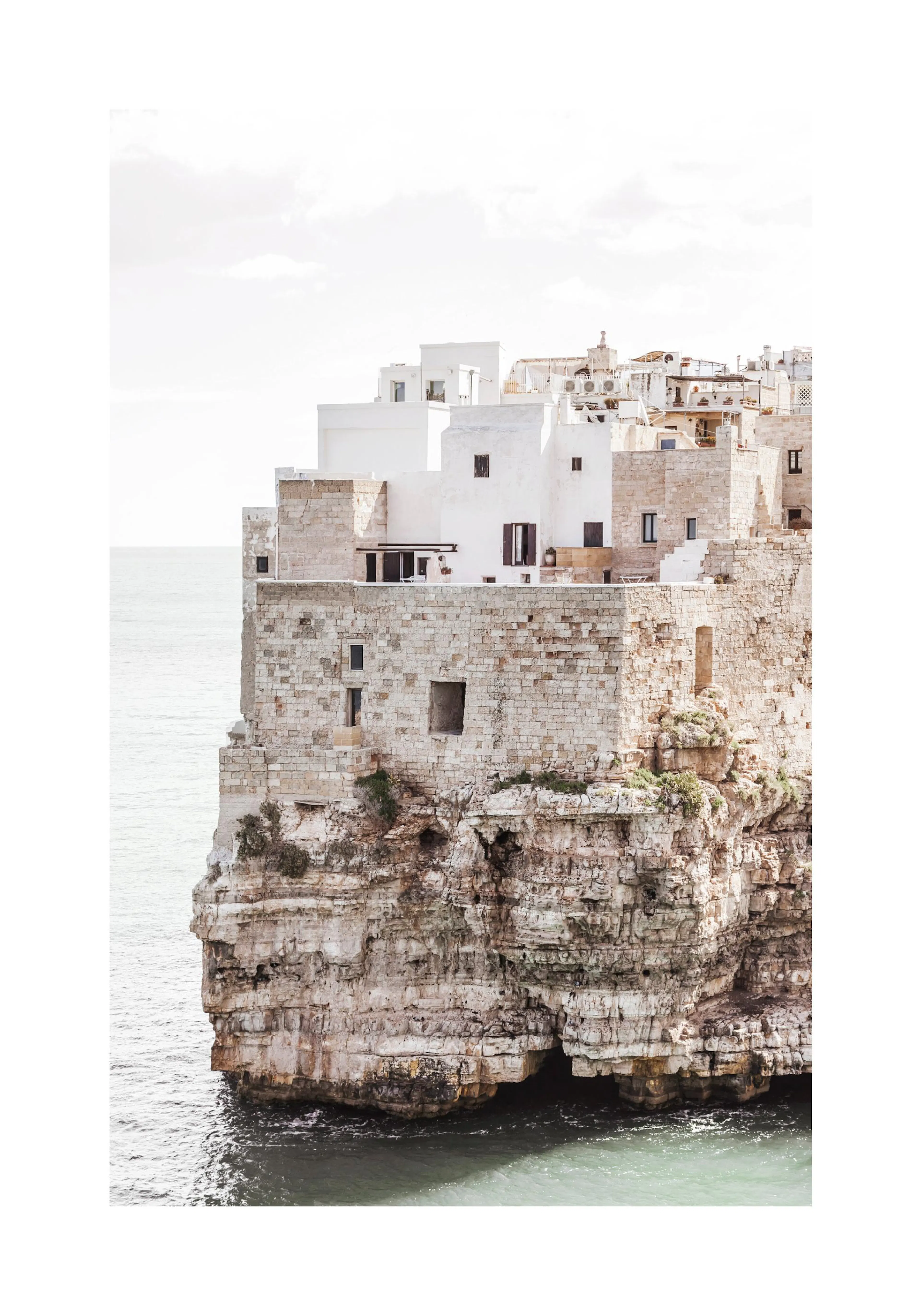 A poster featuring Polignano a Mare, Italy, with white buildings on a rocky cliff overlooking the sea.