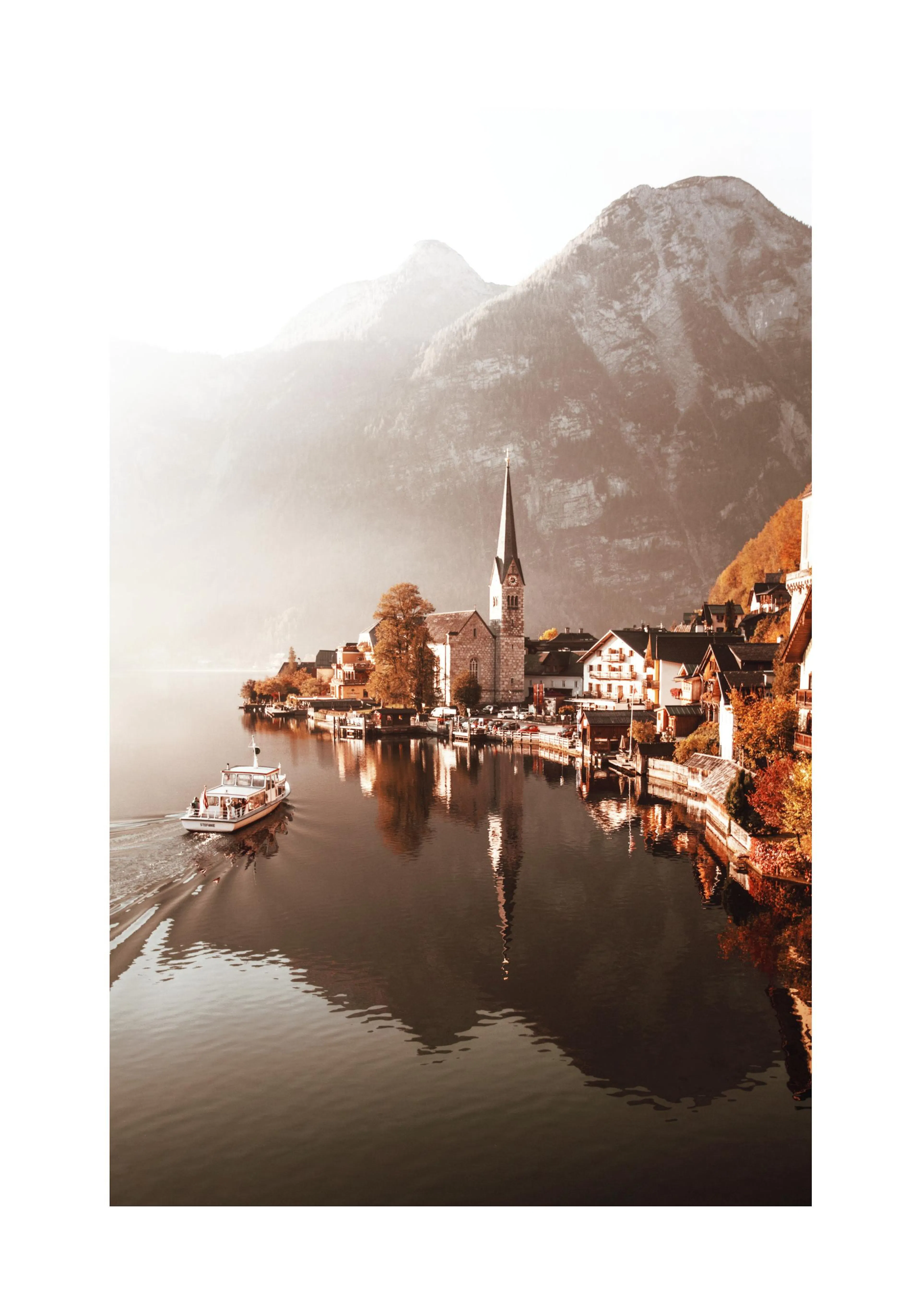 En plakat av Hallstatt, Østerrike, med en landsby ved innsjøen, en kirke og fjell i bakgrunnen.