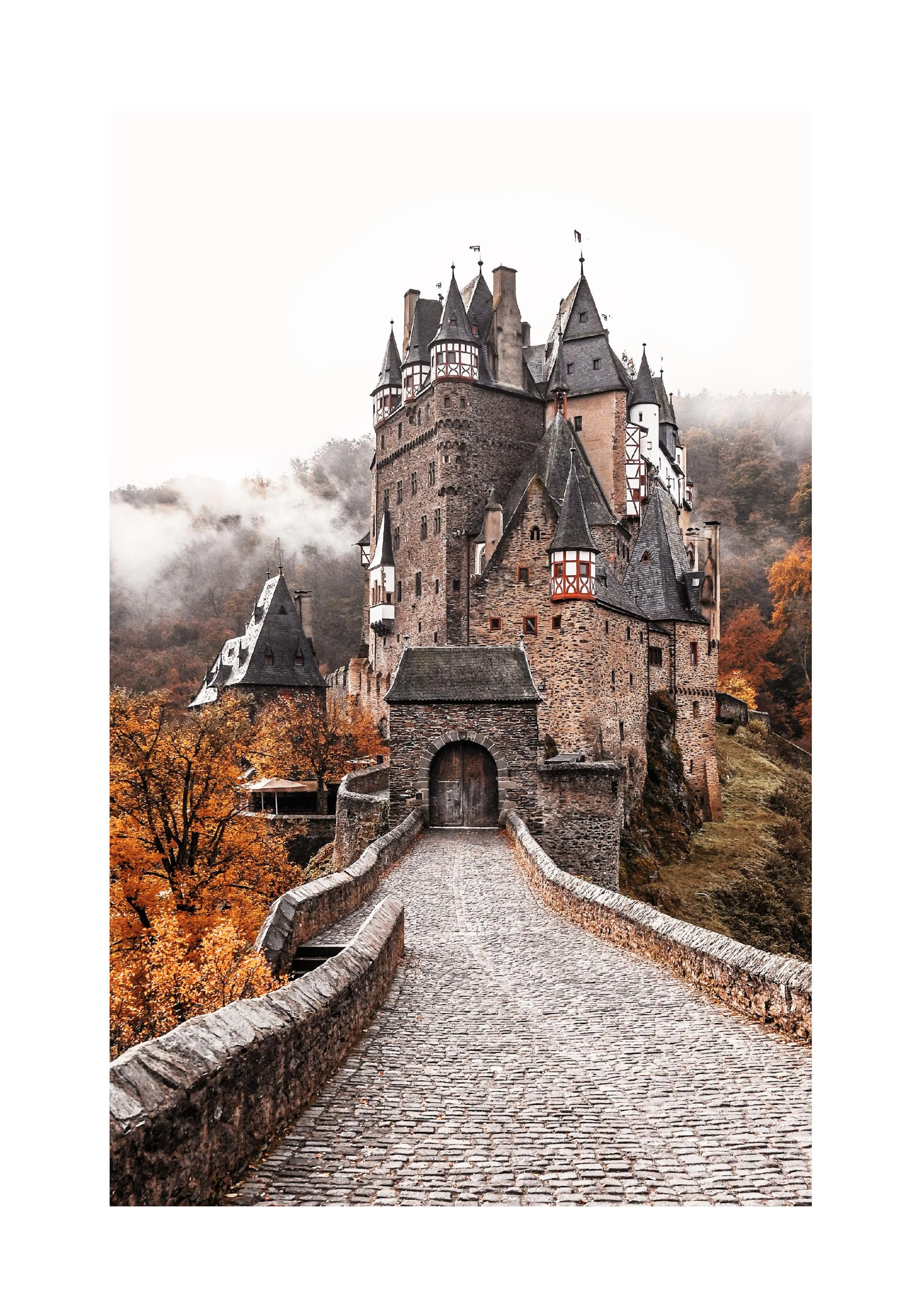 A poster featuring Eltz Castle on a misty autumn day, with colourful trees surrounding the historic stone structure and a long c