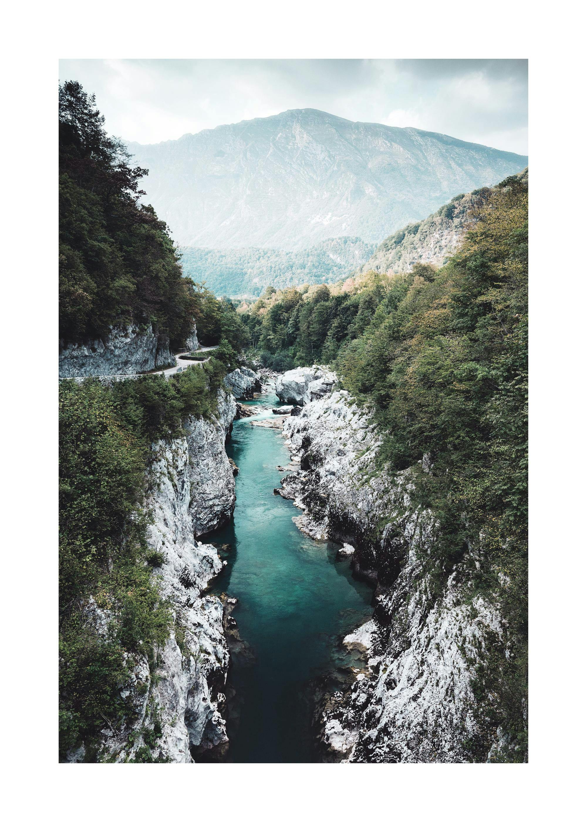 A poster featuring a turquoise river flowing through a rocky canyon with lush green trees and a mountain in the background.