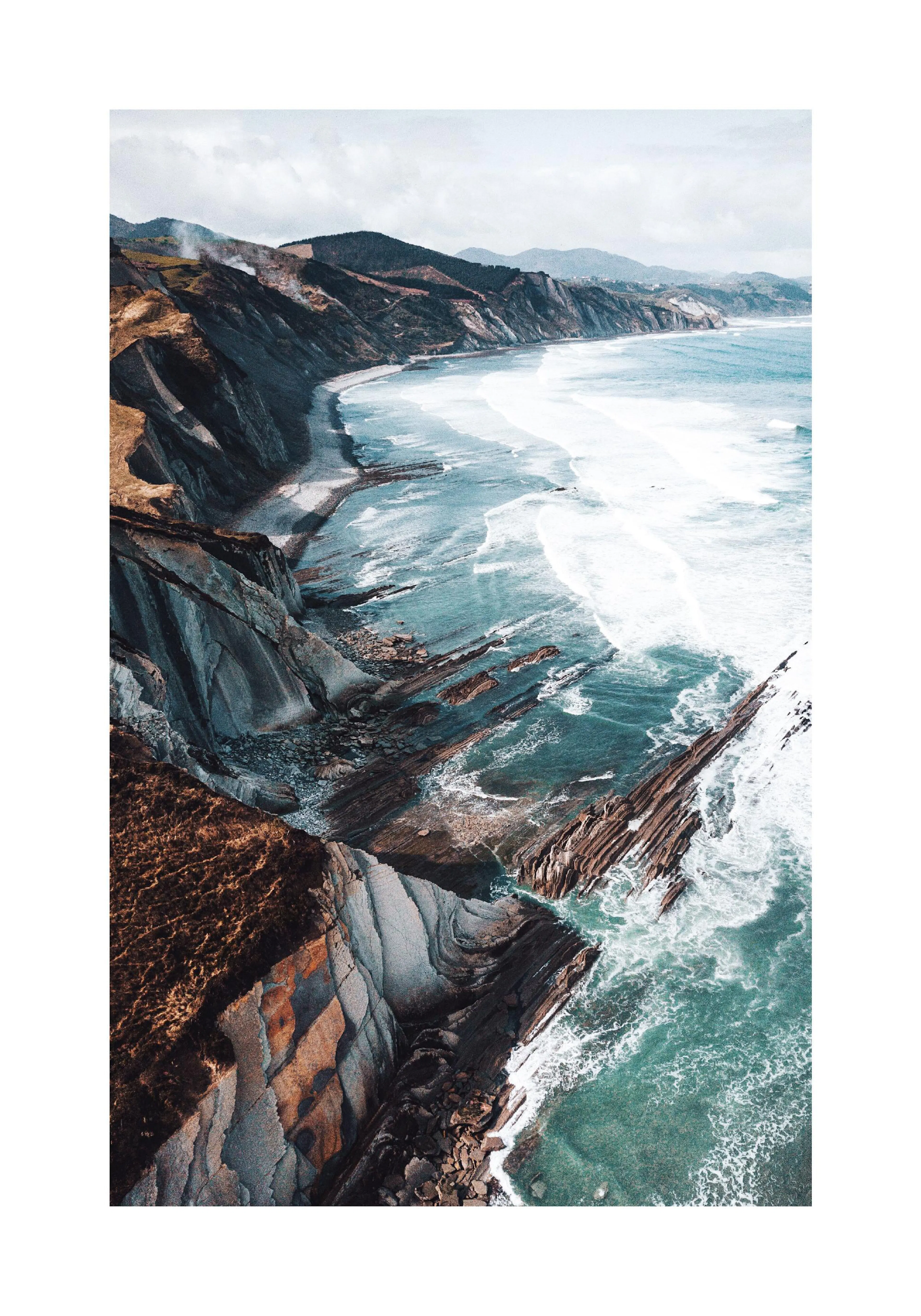 A poster featuring a dramatic coastline with steep, layered rock formations meeting the turquoise ocean waves.